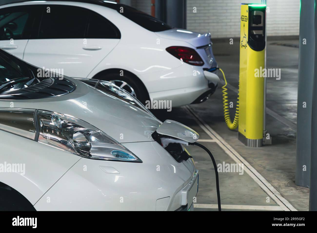 Elektroautos werden von der Ladestation in der Parkgarage des Einkaufszentrums geladen Stockfoto