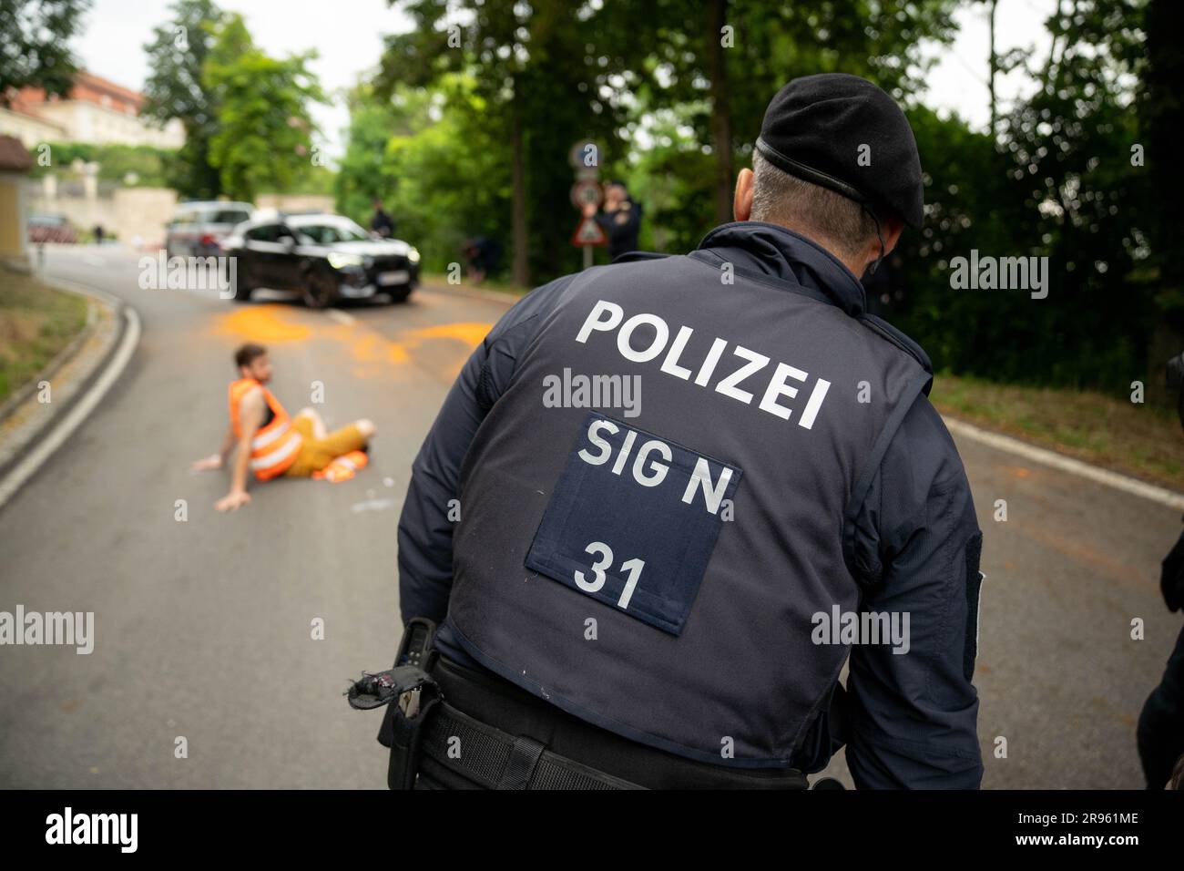 Stift Göttweig/Furth bei Göttweig, Österreich. 24. Juni 2023 Klimaaktivist der Gruppe Last Generation Austria "Letzte Generation Österreich", auf die Straße geklebt, blockiert den Konvoi des bulgarischen Präsidenten und angeblich des österreichischen Kanzlers Karl Nehammer nach einem europäischen Gipfel im Schloss. ©Andreas Stroh Stockfoto