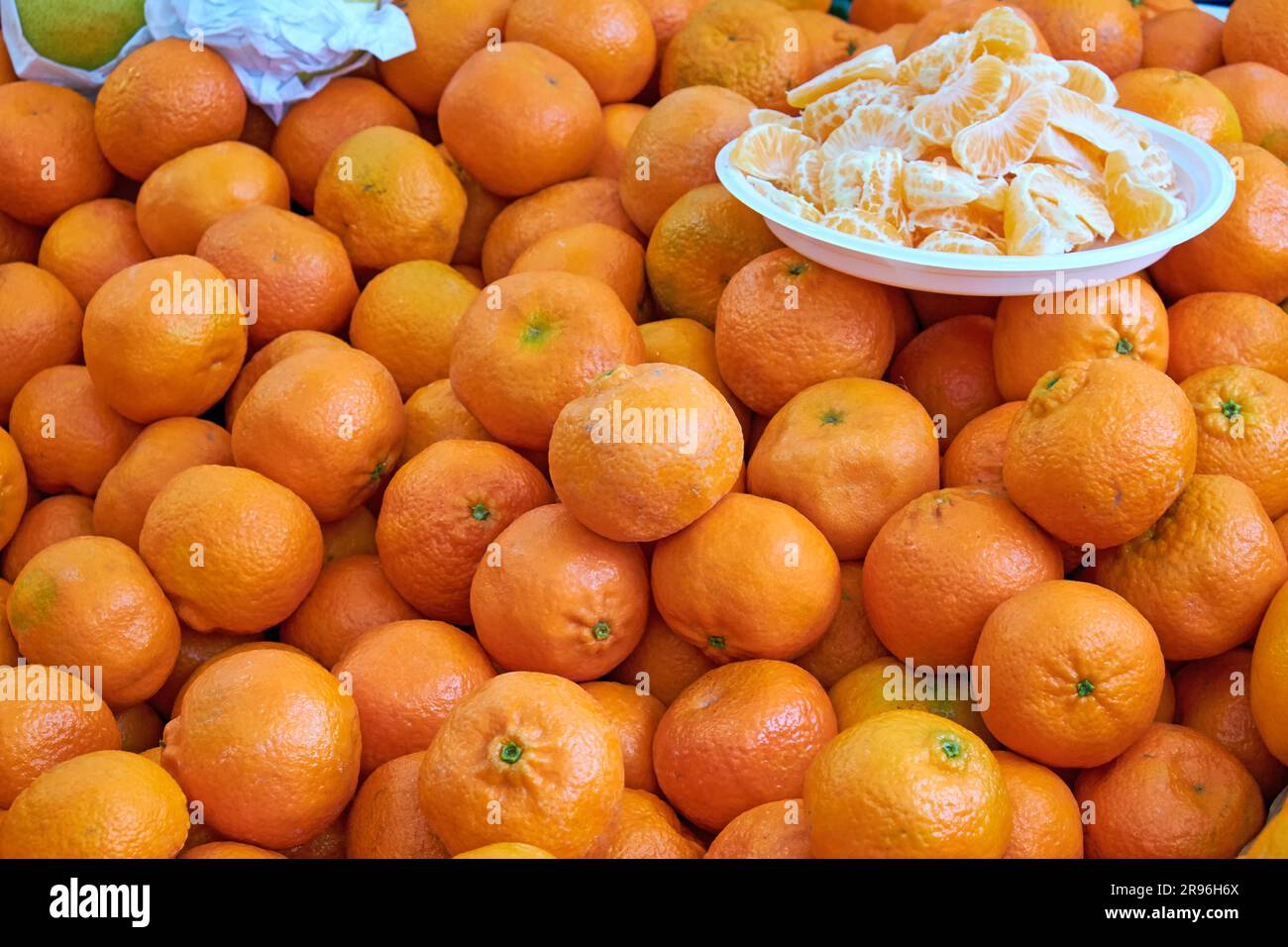 Mandarinen zum Verkauf auf einem Markt mit ein paar Stücken auf einem Teller Stockfoto