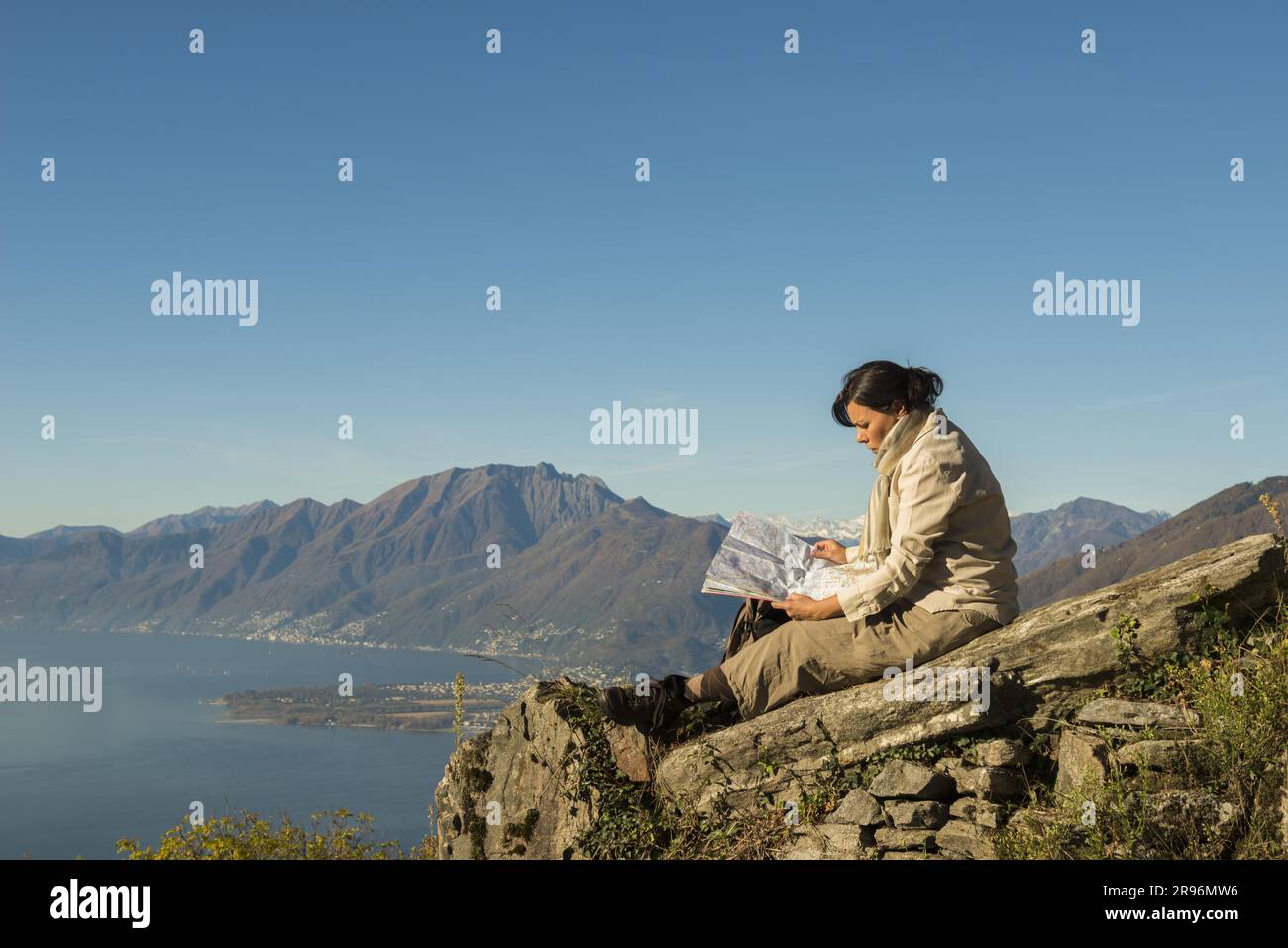 Frau auf einem Berg Entspannen, Lesen einer Karte, See Lago Maggiore im Hintergrund, Tessin, Schweiz Stockfoto