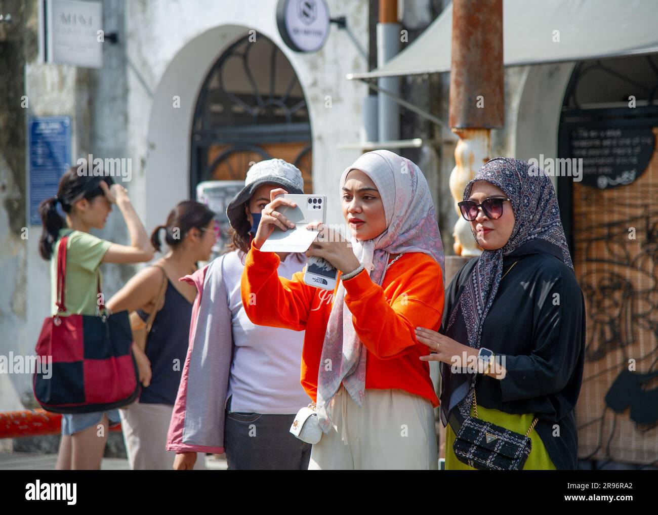 Februar 24 2023 - George Town - Penang - Malaysia - zwei junge Frauen in Orange und Schwarz mit einem traditionellen Schal auf dem Kopf machen Fotos Stockfoto