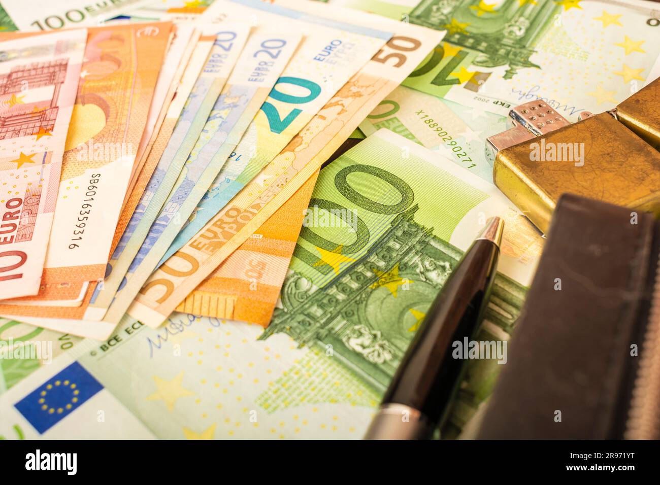 Goldener Feuerzeugwecker auf dem Hintergrund von grünem Geld 100-Euro-Scheine Stockfoto