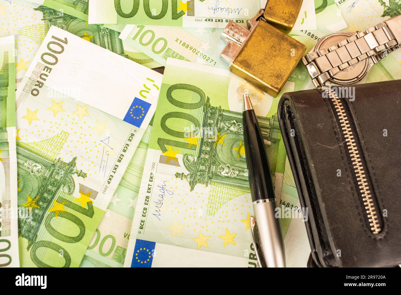 Goldener Feuerzeugwecker auf dem Hintergrund von grünem Geld 100-Euro-Scheine Stockfoto Goldener Feuerzeugwecker auf dem Hintergrund von grünem Geld 100-Euro-Scheine Stockfoto