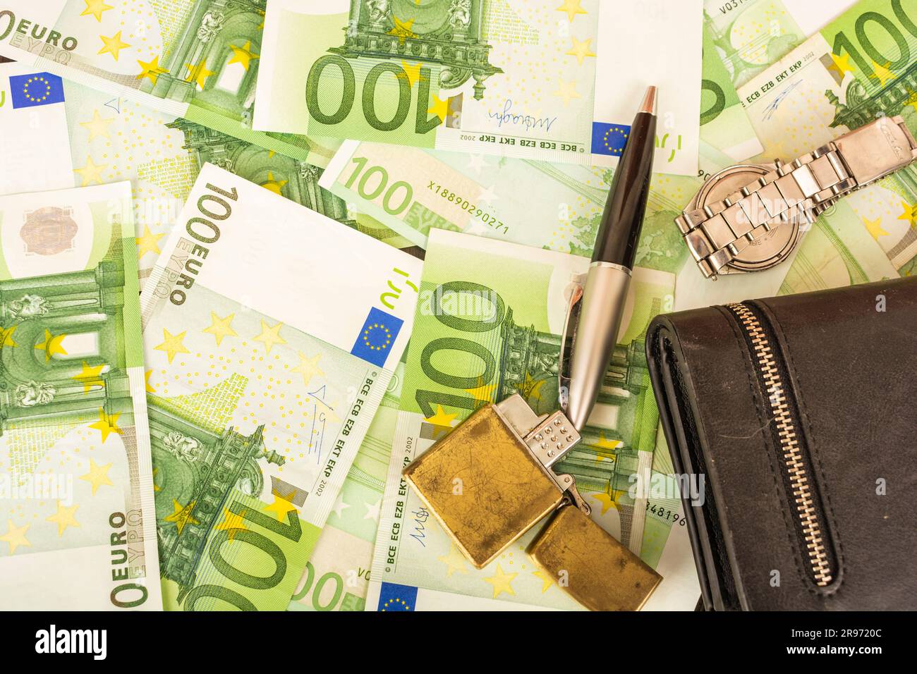 Goldener Feuerzeugwecker auf dem Hintergrund von grünem Geld 100-Euro-Scheine Stockfoto