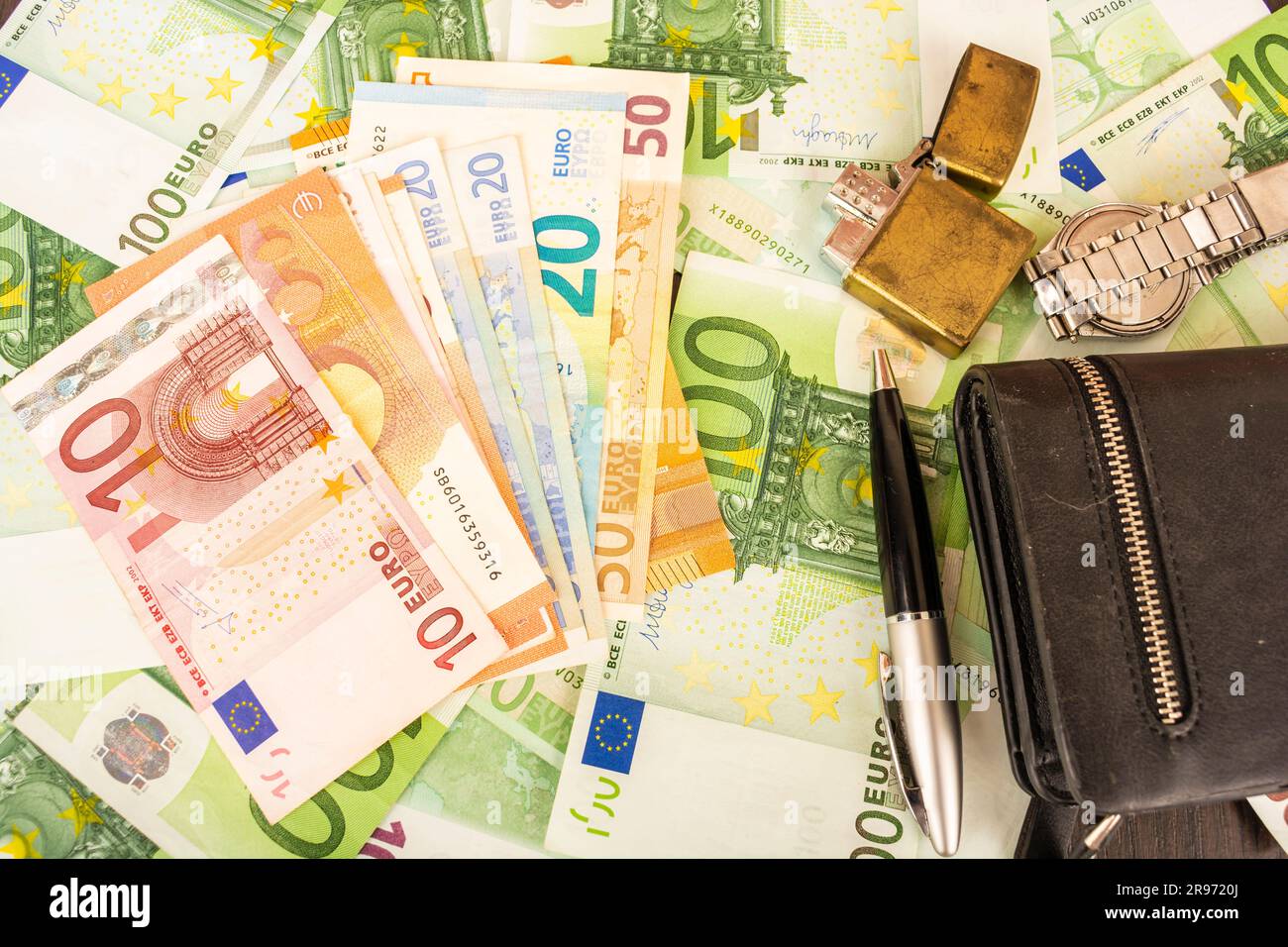 Goldener Feuerzeugwecker auf dem Hintergrund von grünem Geld 100-Euro-Scheine Stockfoto Goldener Feuerzeugwecker auf dem Hintergrund von grünem Geld 100-Euro-Scheine Stockfoto