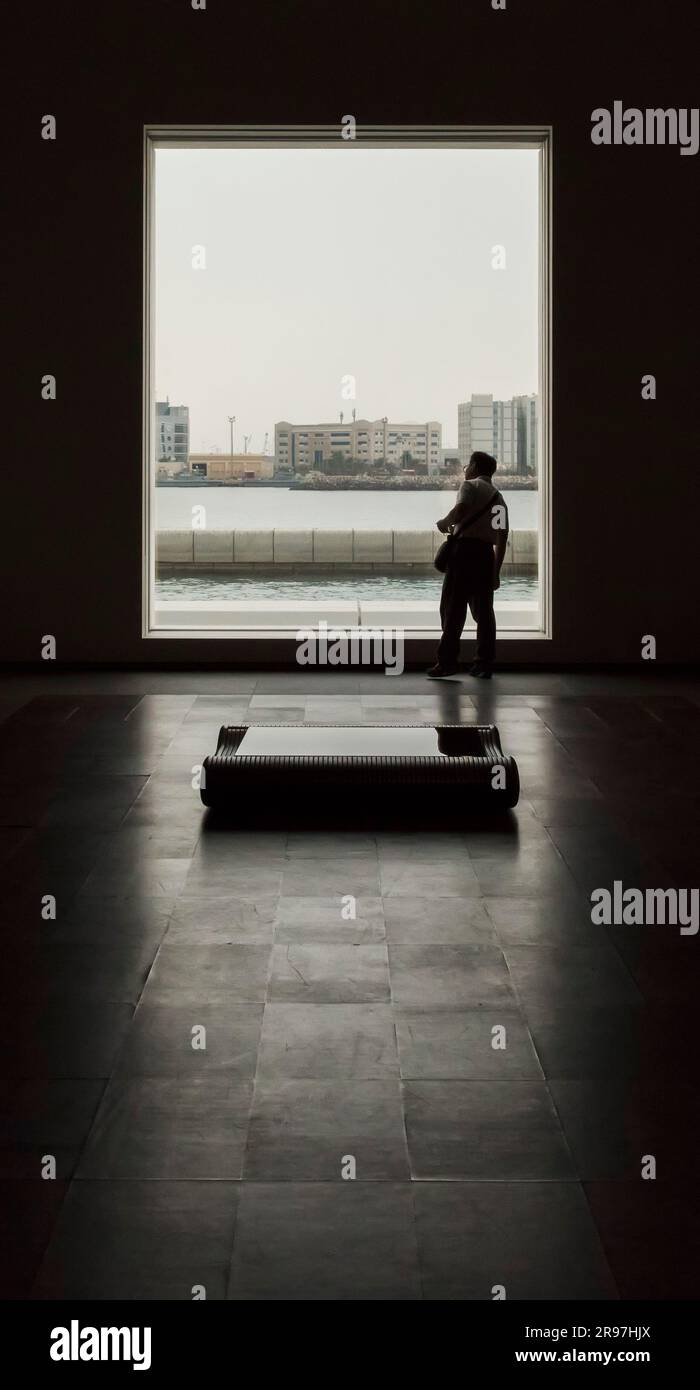 Ein Mann blickt durch das Fenster auf das Louvre Museum, Abu Dhabi, VAE Stockfoto