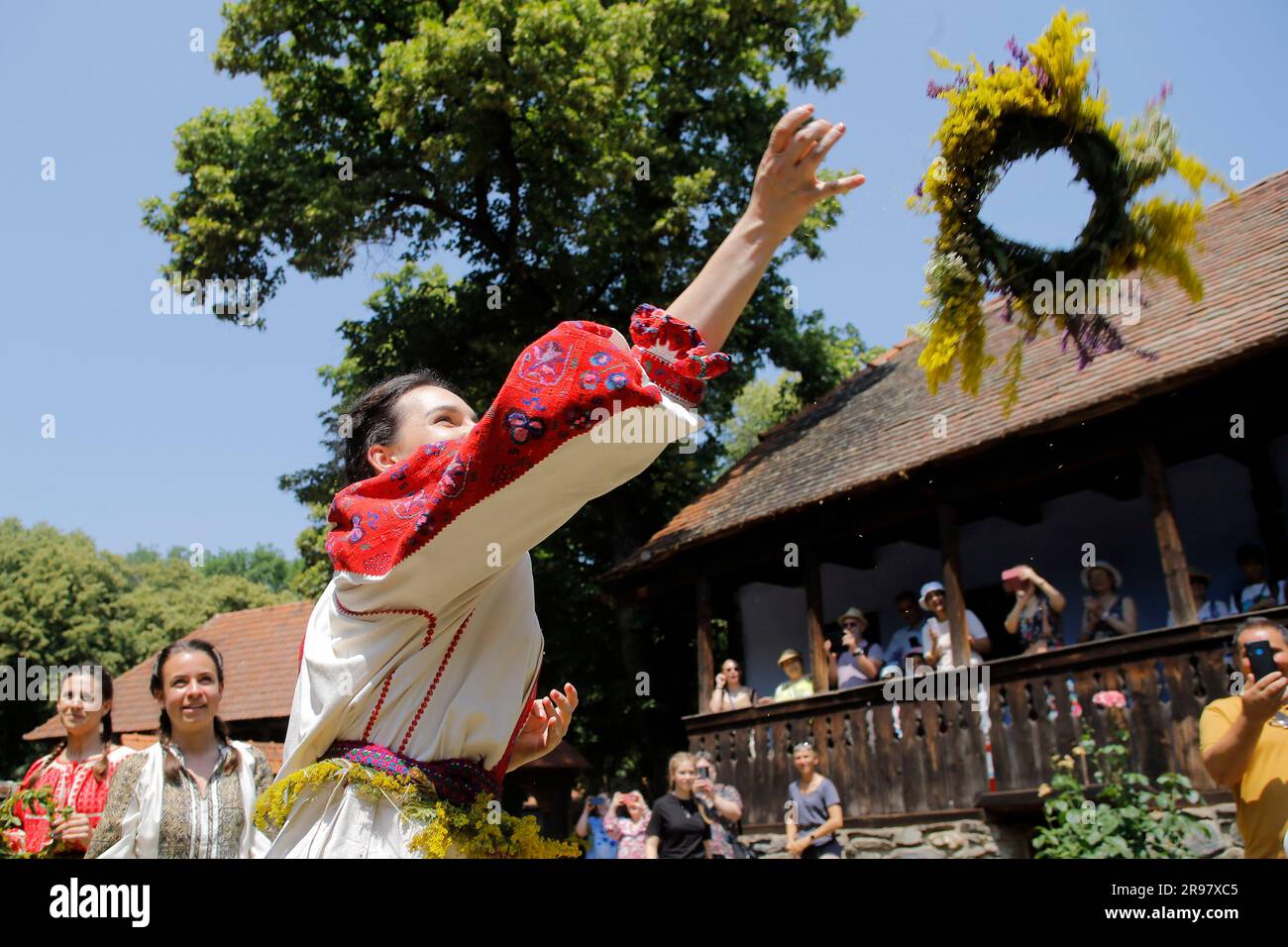 Bukarest, Rumänien. 24. Juni 2023. Ein junges Mädchen, das als Fee verkleidet ist, wirft ihren Kranz auf das Dach eines Hauses, um zu sehen, ob sie dieses Jahr während des traditionellen Volksfestivals „Sanziene“ in Bukarest, Hauptstadt von Rumänien, am 24. Juni 2023 heiraten wird. Alte Traditionen erwähnen „Sanzienele“ als sanfte Feen, die um die Sommersonnenwende kommen, um Glück und gute Ernte zu bringen. Kredit: Cristian Cristel/Xinhua/Alamy Live News Stockfoto