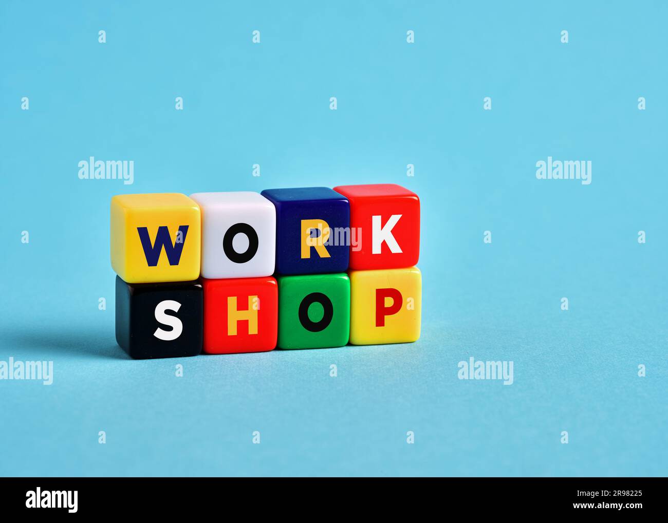Das Wort Workshop über bunte Würfel auf blauem Hintergrund. Stockfoto