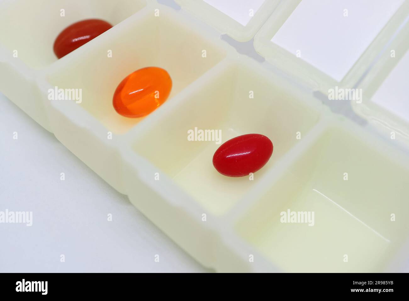 Geöffneter Tragetasche für Pillen-Organisatoren mit verschiedenen Ergänzungspillen isoliert auf weißem Hintergrund Stockfoto