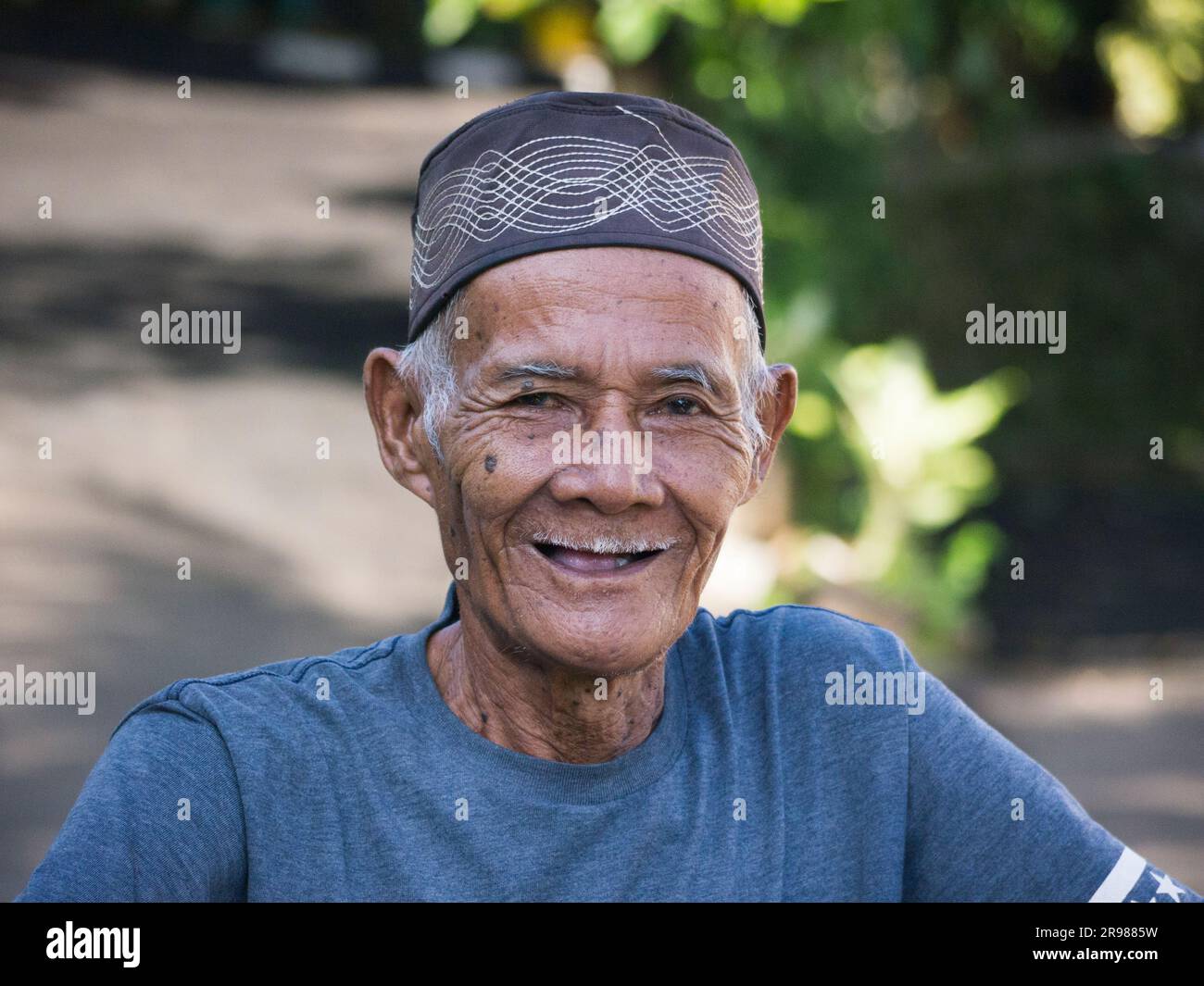 Jakarta, Indonesien - 20. Juni 2023 : Porträt eines asiatischen Seniorenmannes mit schwarzer Schädelkappe und grauen Haaren, die vor der Kamera lächeln Stockfoto