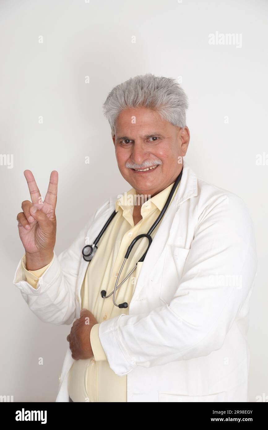 Leitende Ärztin im Laborkittel mit überkreuzten Armen vor weißem Hintergrund. Glücklicher indischer Arzt im weißen Mantel. Selbstbewusst. Stockfoto