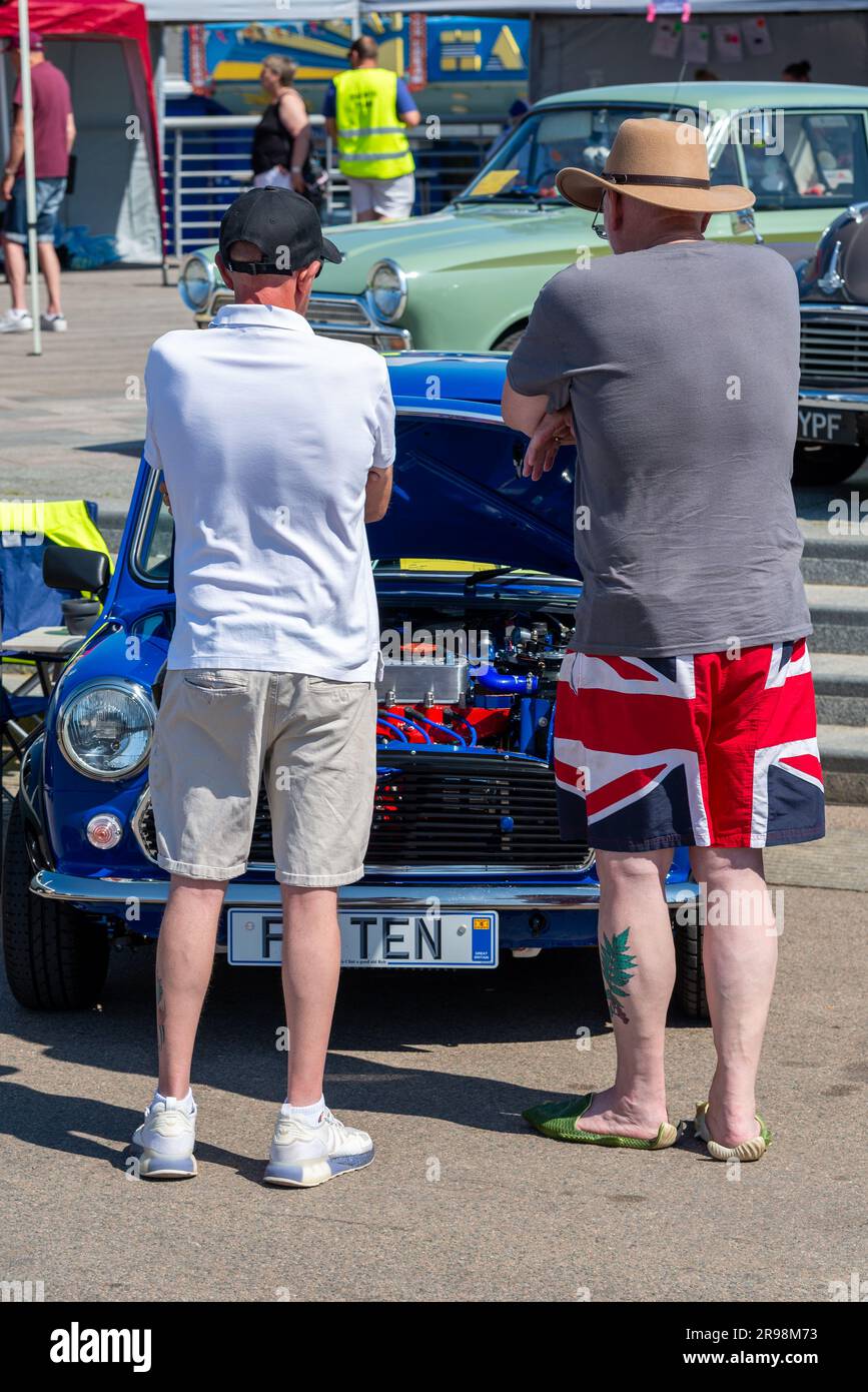 Southend on Sea, Essex, Großbritannien. 25. Juni 2023. Die Leute genießen den warmen, sonnigen Morgen in der Küstenstadt. Ein Oldtimer-Event zieht Aufmerksamkeit auf sich. Enthusiasten, die einen britischen Rover Mini inspizieren Stockfoto