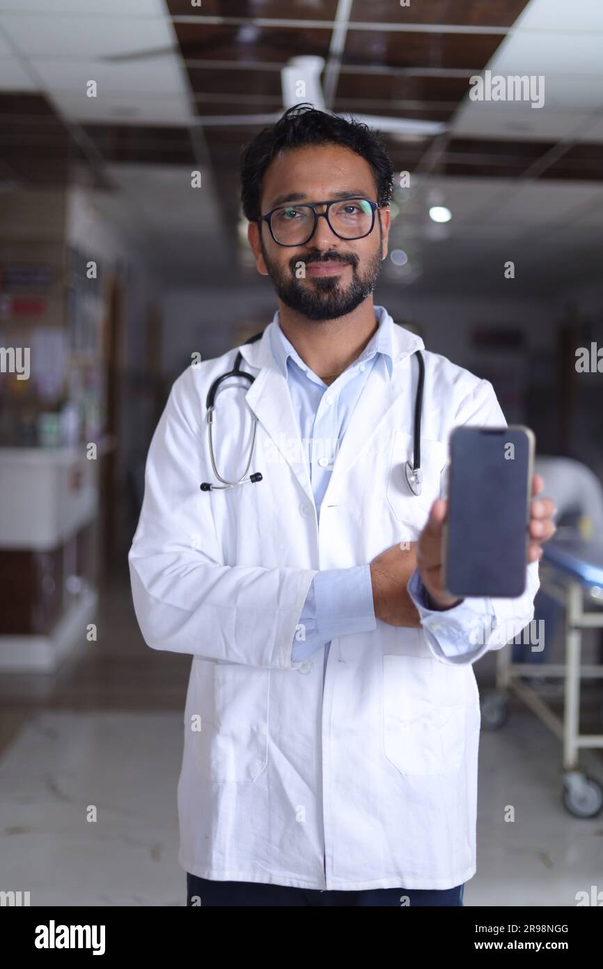 Arzt im Krankenhaus. Oberarzt mit Stethoskop im Klinikkorridor. Medizin, Personal, Gesundheitsfürsorge, Gesundheitsdienst. Speicherplatz kopieren. Mobile App wird angezeigt. Stockfoto