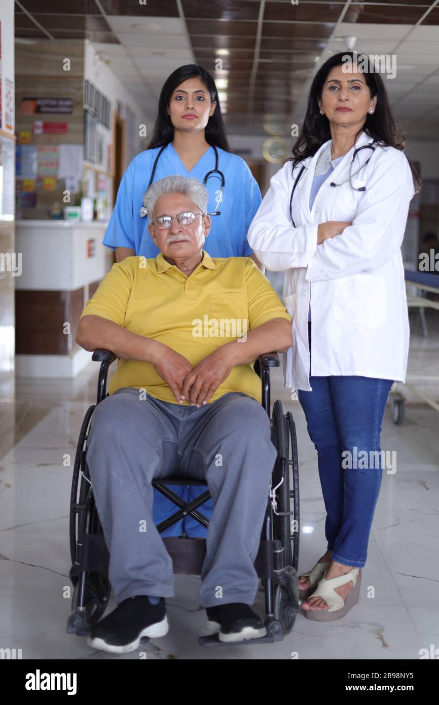 Indische Krankenschwester sieht sehr glücklich aus, grüßt einen älteren Patienten im Rollstuhl im Krankenhaus und lächelt - Healthcare-Konzepte. Stockfoto