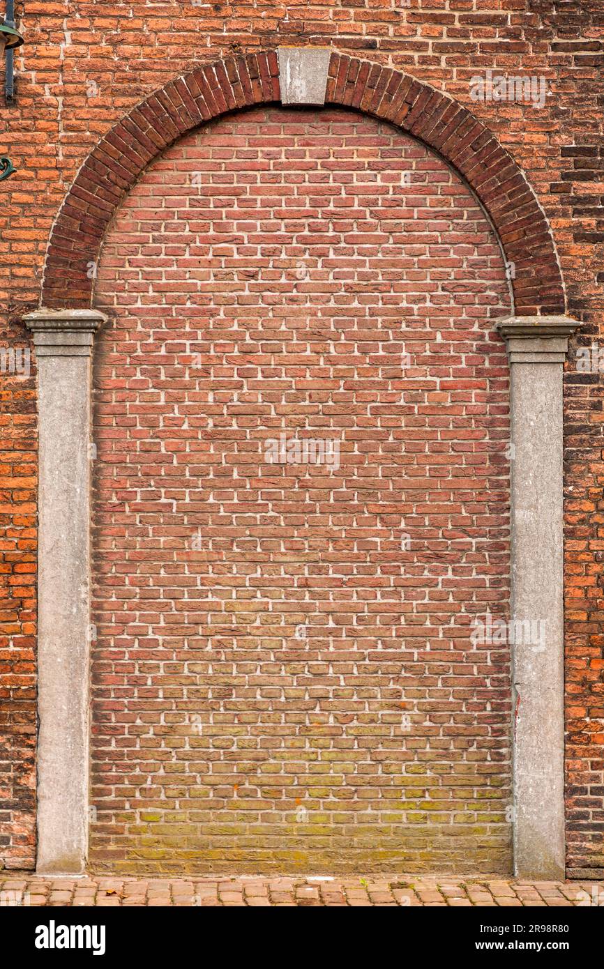 Roter Backsteinwandfragment mit Bogenform, architektonische Details Stockfoto