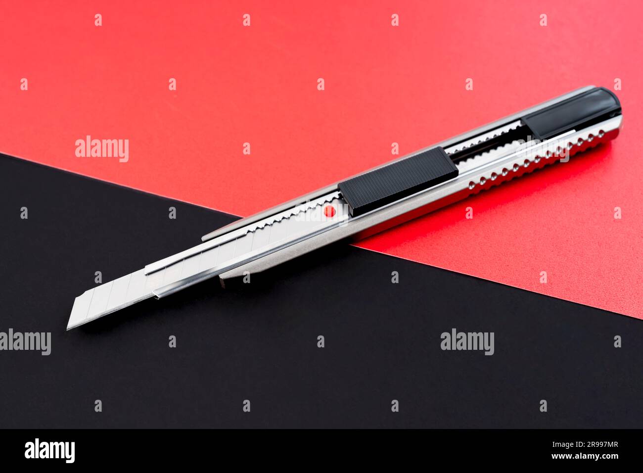 Ein Cutter- oder Schreibmesser auf schwarzem und rotem Hintergrund. Stockfoto