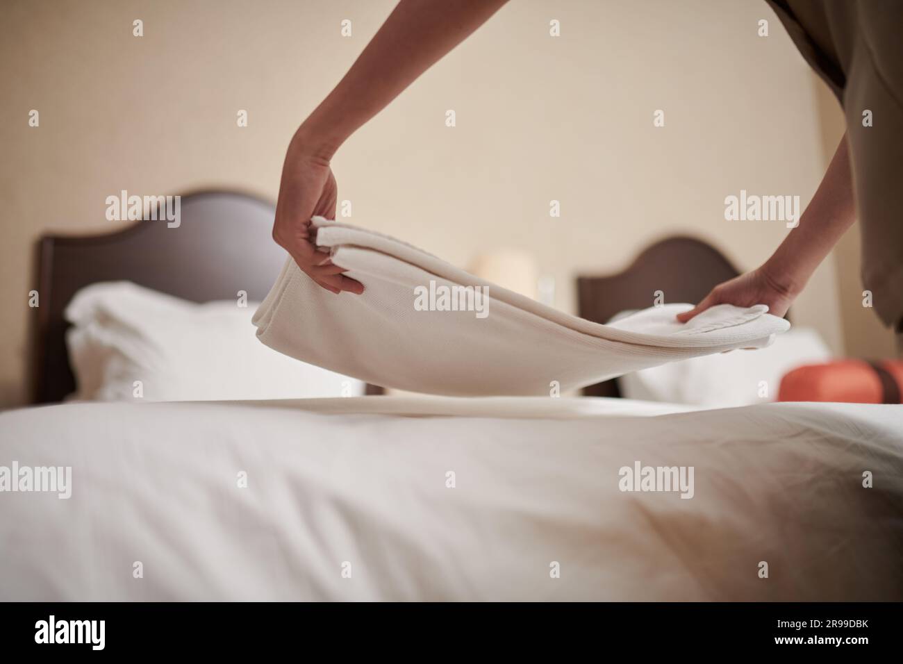Die Hände des Zimmermädchens legten frische Bettwäsche auf das Bett im Hotelzimmer Stockfoto