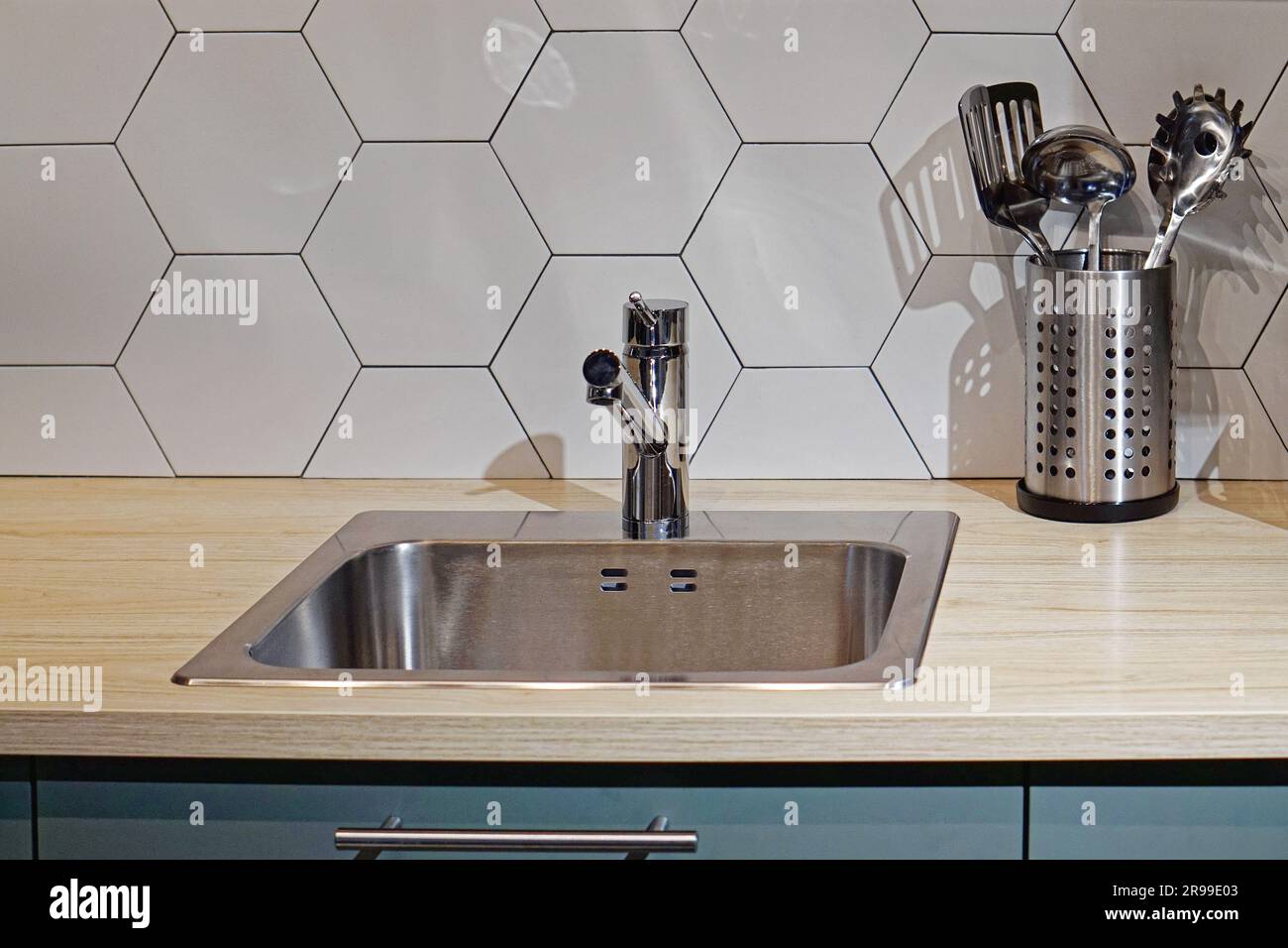 Modernes Küchenspüle aus Edelstahl und Wasserhahn an der Holztheke Stockfoto