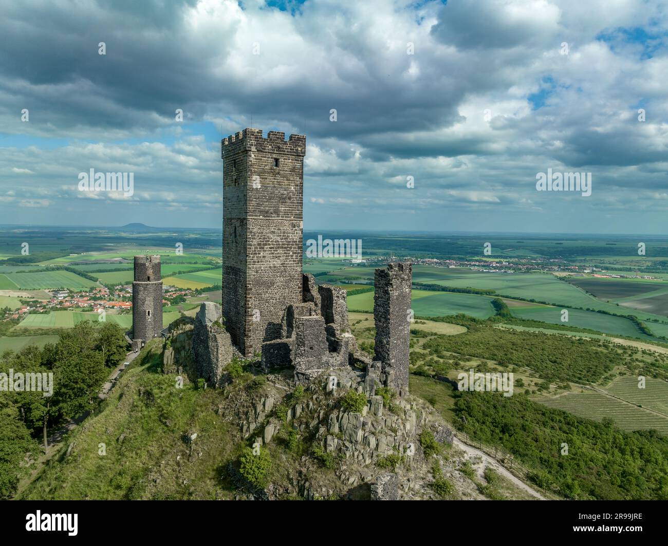 Die Überreste der mittelalterlichen Burg Hazmburk aus der Vogelperspektive mit einem runden und rechteckigen Turm befinden sich auf dem Gipfel dieses Niedriggipfels mit Landschaft Stockfoto
