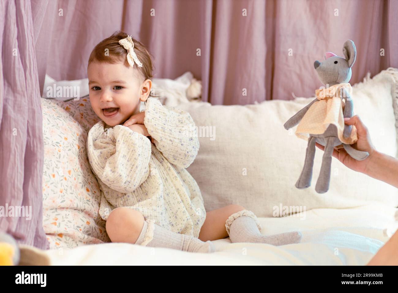 Das Baby hat Angst vor dem Stoffmaus, das seine mutter ihr schenkt Stockfoto