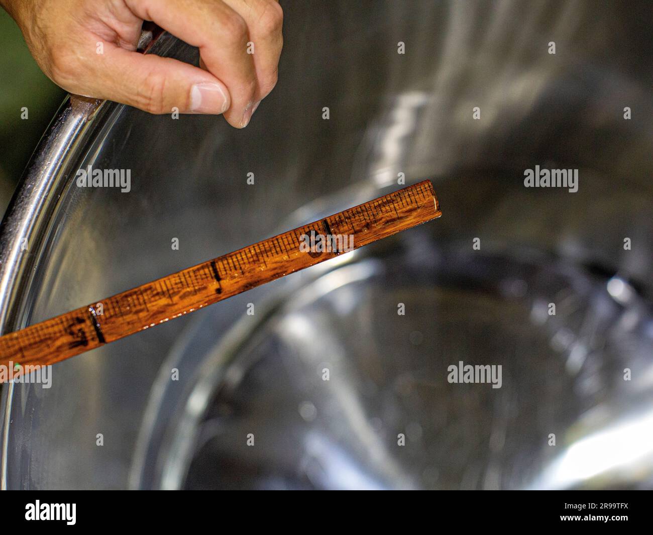 Hand mit Holzmesserstick, der den Sake mit Wasser verdünnt – um den Alkoholgehalt anzupassen. Akashi, Präfektur Hyogo, Japan. Stockfoto