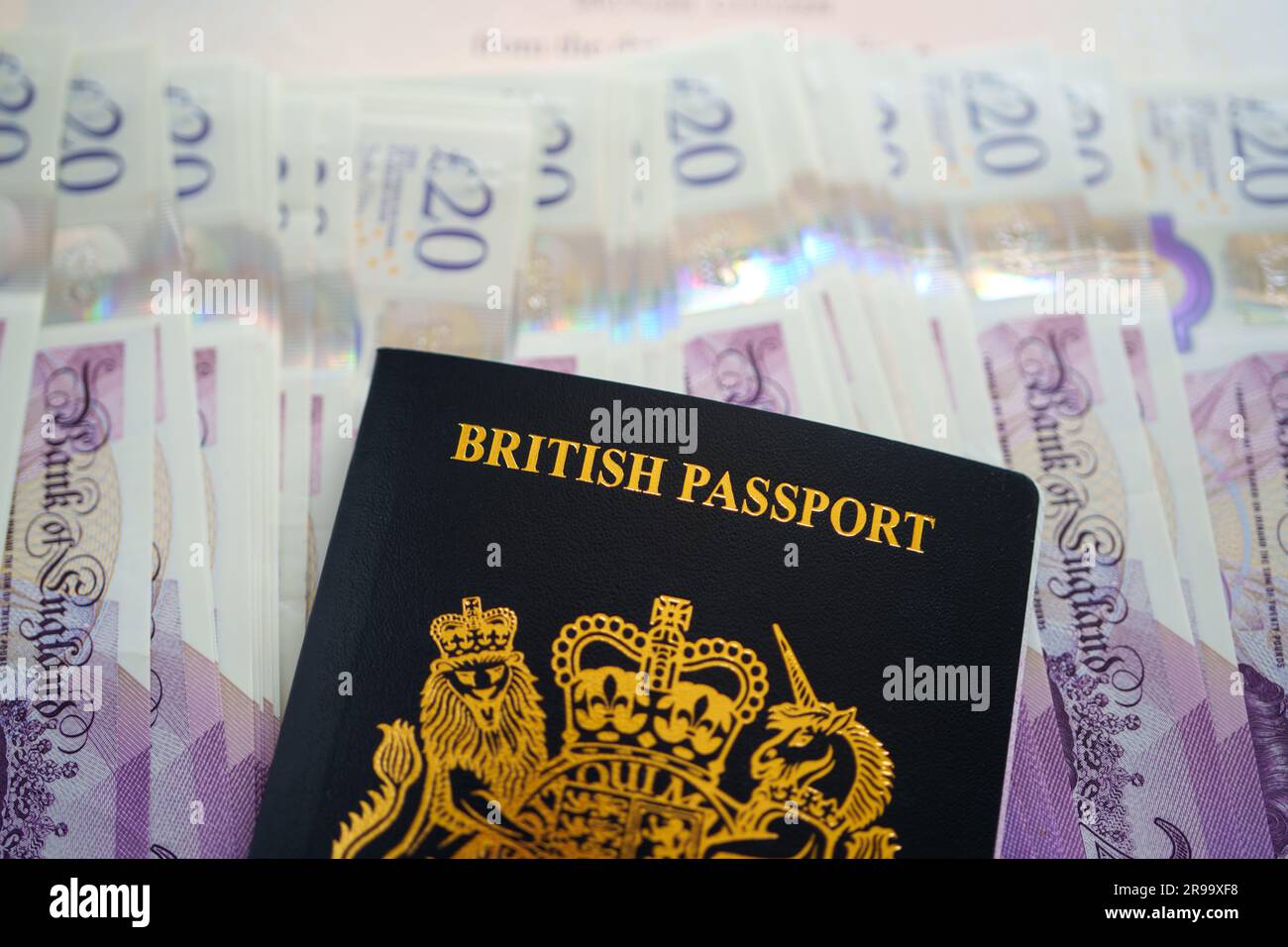 Britischer Pass auf einen Stapel mit 20-Pfund-Noten. Konzept. Stafford, Großbritannien, 25. Juni 2023 Stockfoto