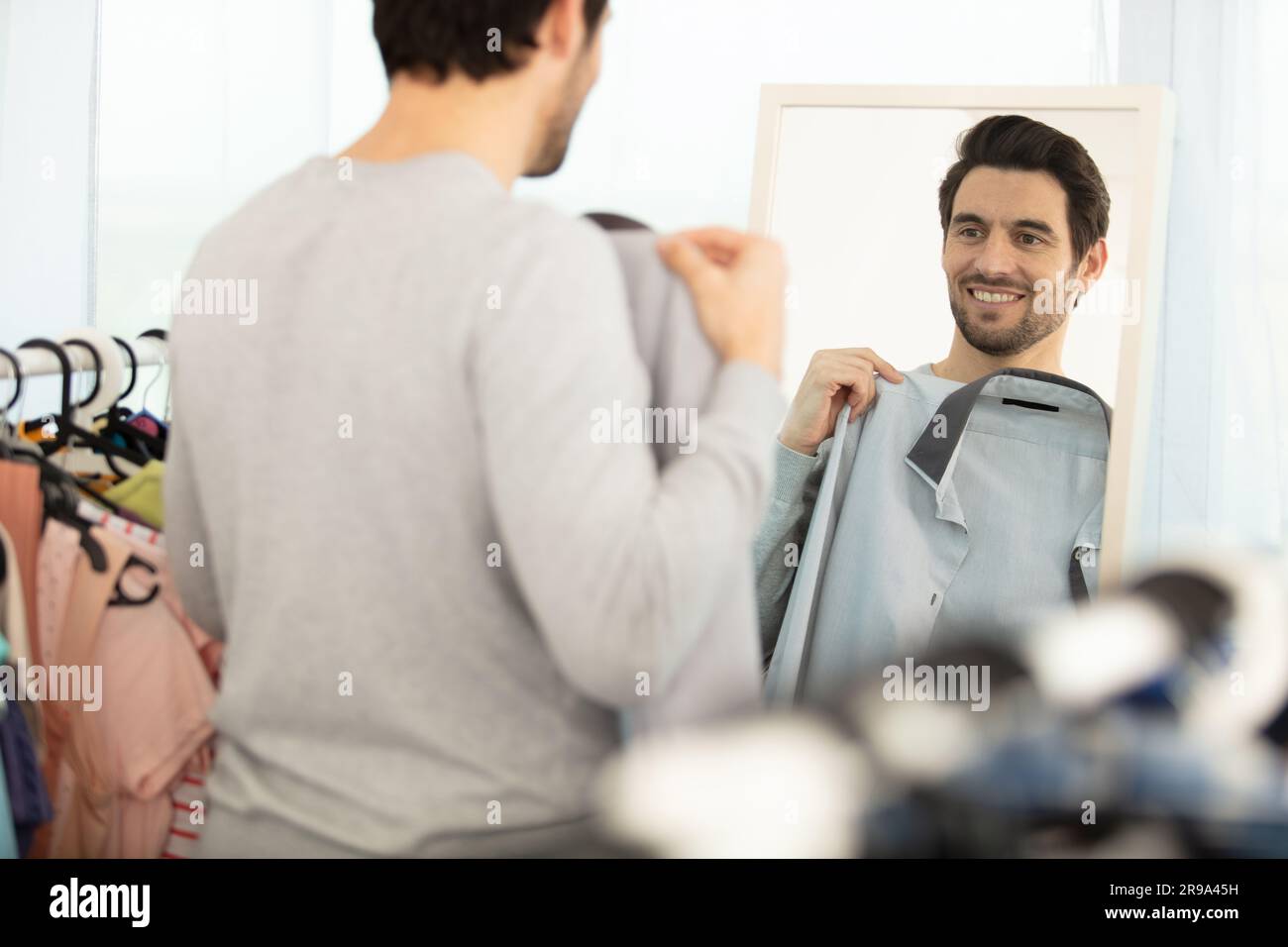 Ein Mann in neuen Outfits, der sich im Spiegel sieht Stockfoto