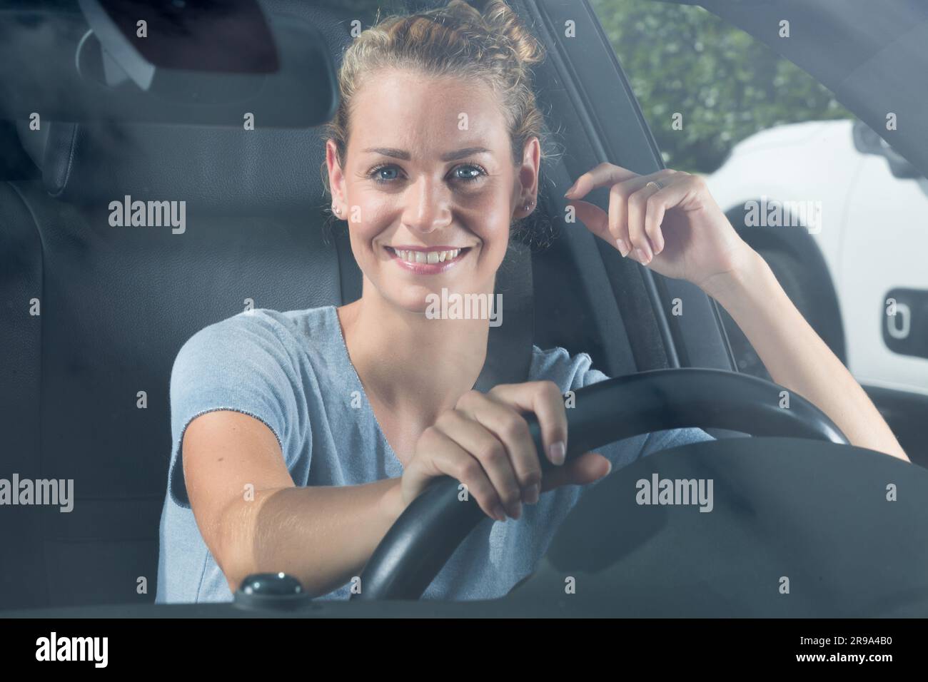 Lächelnde Frau, die in ihrem Auto sitzt Stockfoto