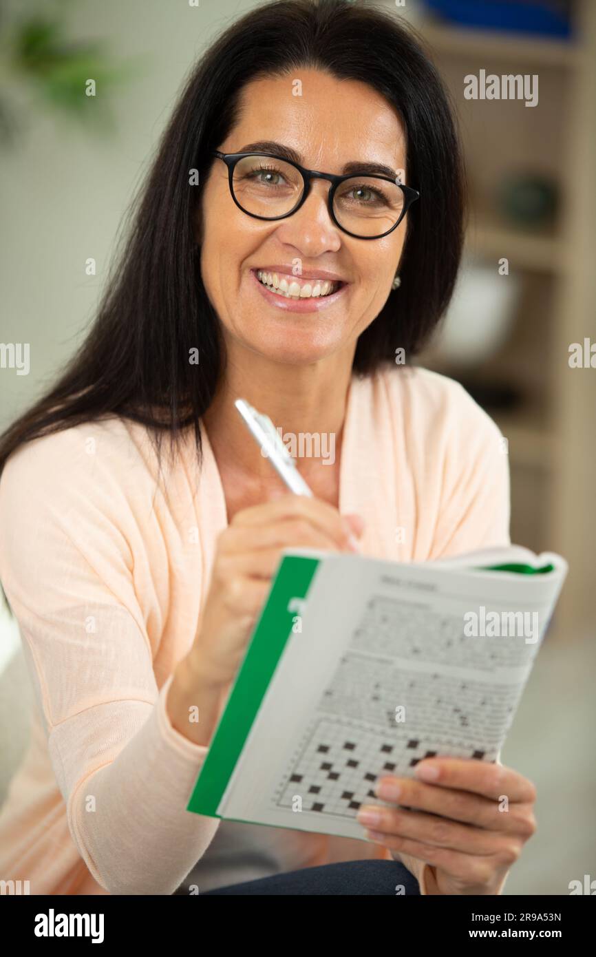 Eine Frau mit Brille, die an einem Kreuzworträtsel arbeitet Stockfoto