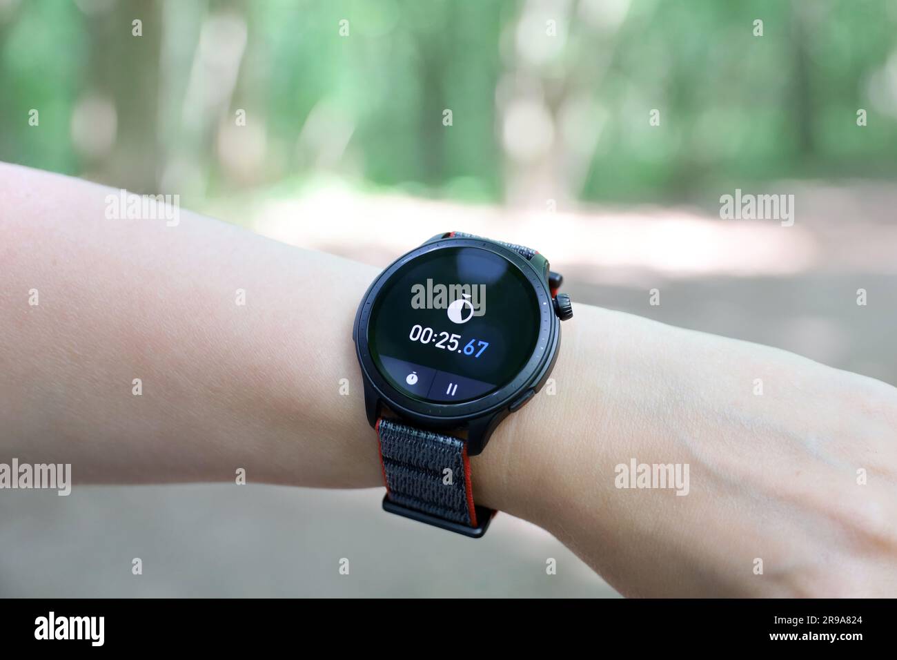Smartwatch an weiblicher Hand mit Stoppuhr. Rundes Display mit App für Sporttraining Stockfoto