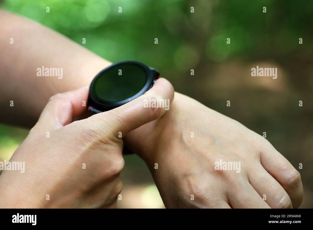 Intelligente Uhr auf weiblicher Hand im Sommerpark. Rundes Display mit Apps für Wandern und Sporttraining Stockfoto