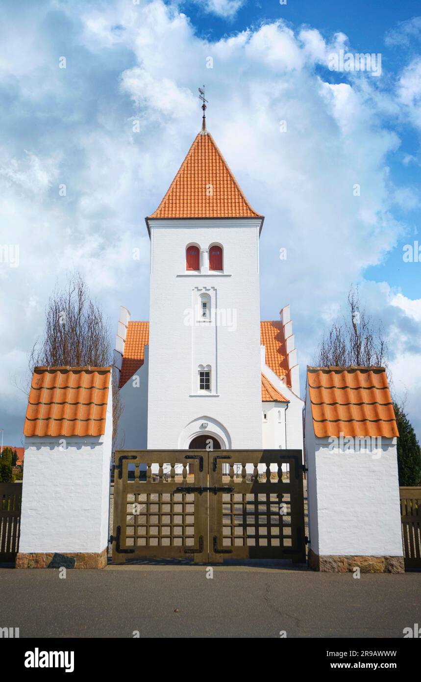 Tor zu einer wunderschönen weißen Kirche mit rotem Ziegeldach unter blauem Himmel Stockfoto