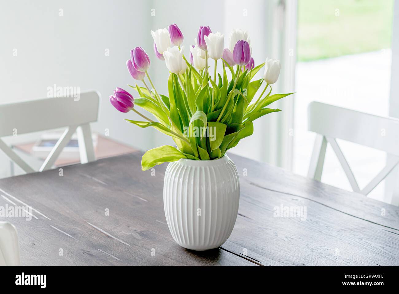 Strauß von Tulpenblumen in einer weißen Vase auf einem Holztisch im Frühling Stockfoto