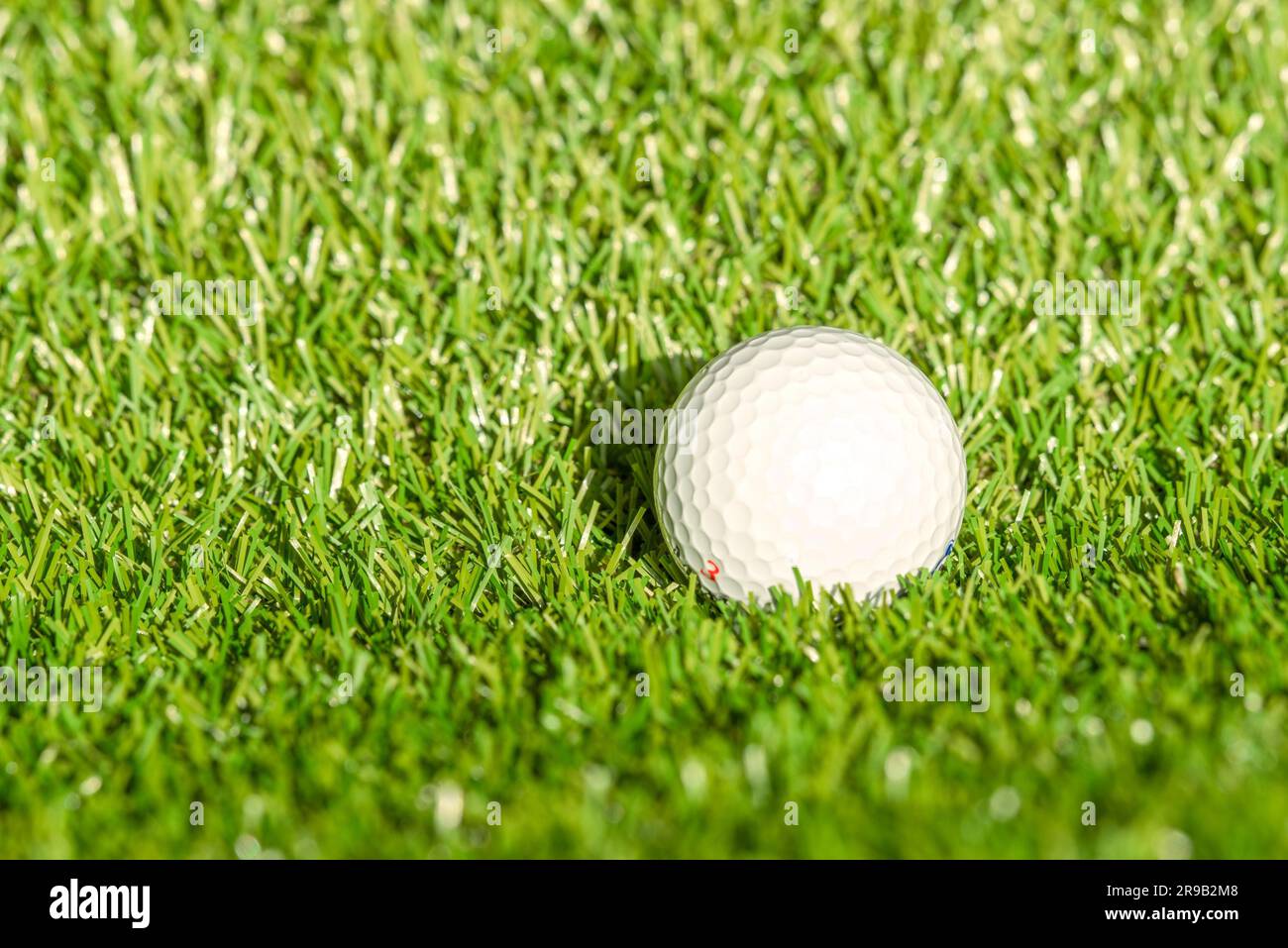 Golfball auf Astro-Rasen bei hellem Tageslicht Stockfoto