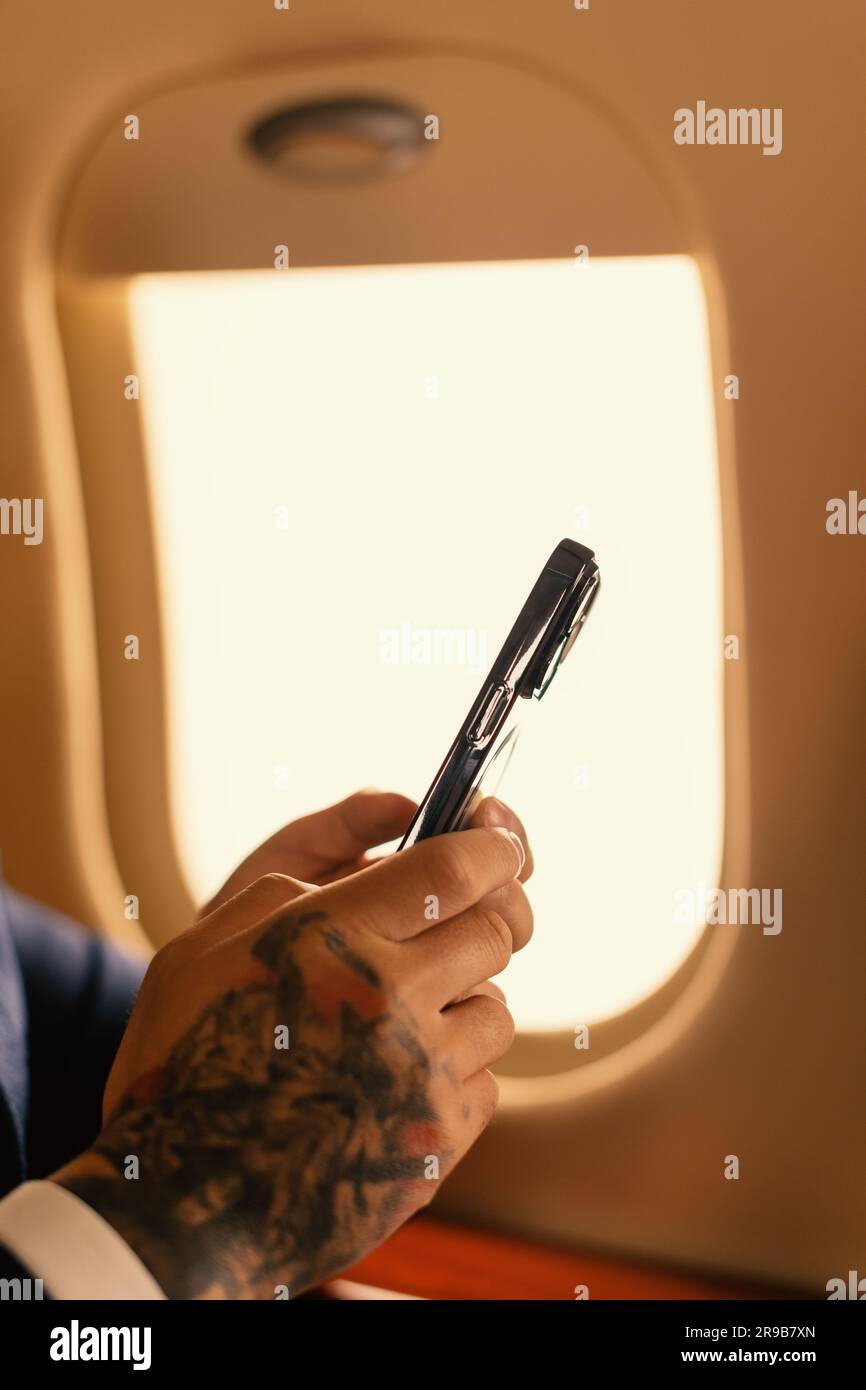 Nahaufnahmen Eleganter Geschäftsmann, der mit einem modernen Smartphone arbeitet, das in einem erstklassigen Privatflugzeug Jet, Travel und Airline Concept sitzt Stockfoto