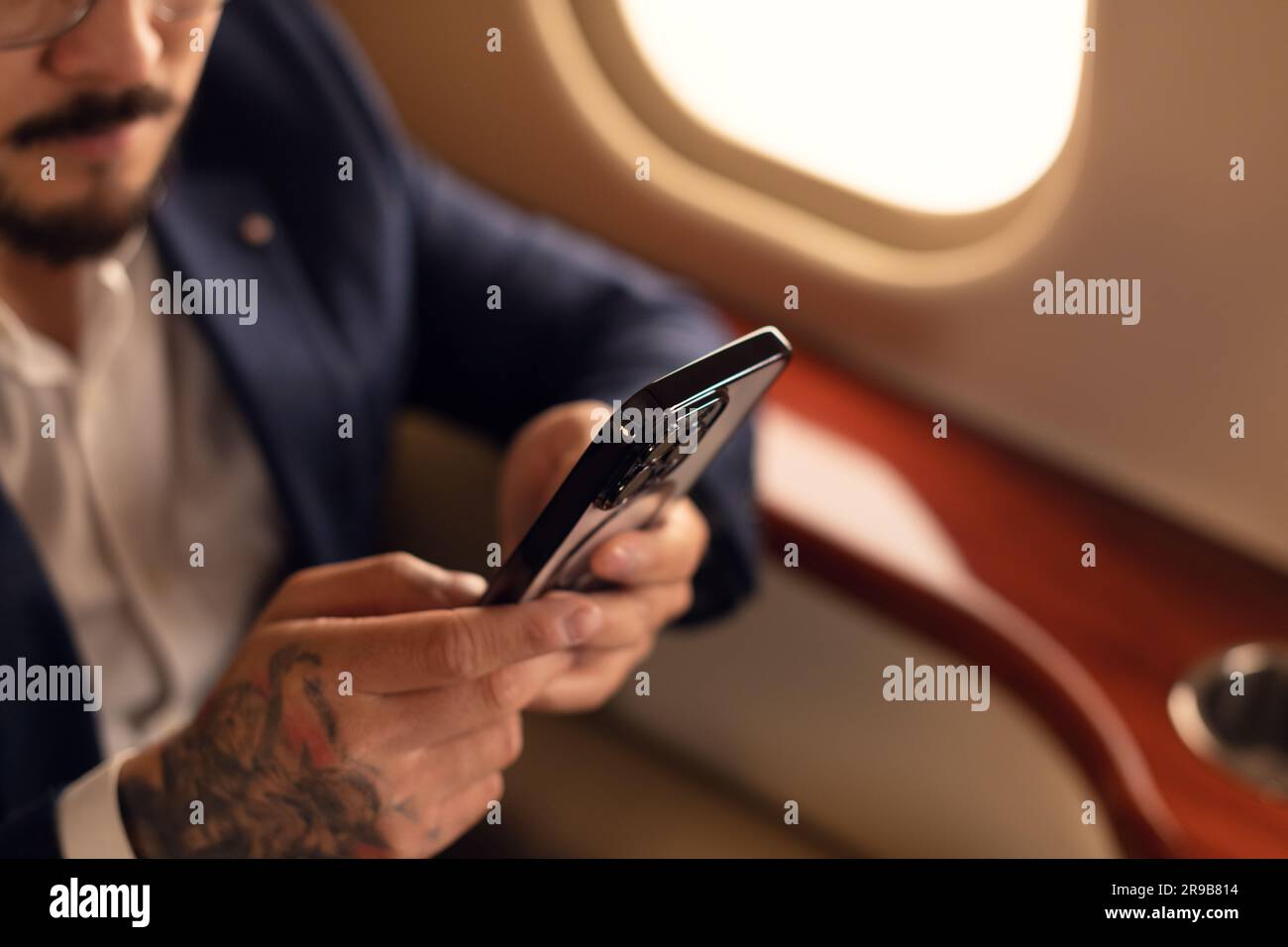 Nahaufnahme eines nicht erkennbaren Geschäftsmannes mit einem modernen Smartphone in einem erstklassigen Privatflugzeug-JET, Travel und Airline-Business-Konzept Stockfoto