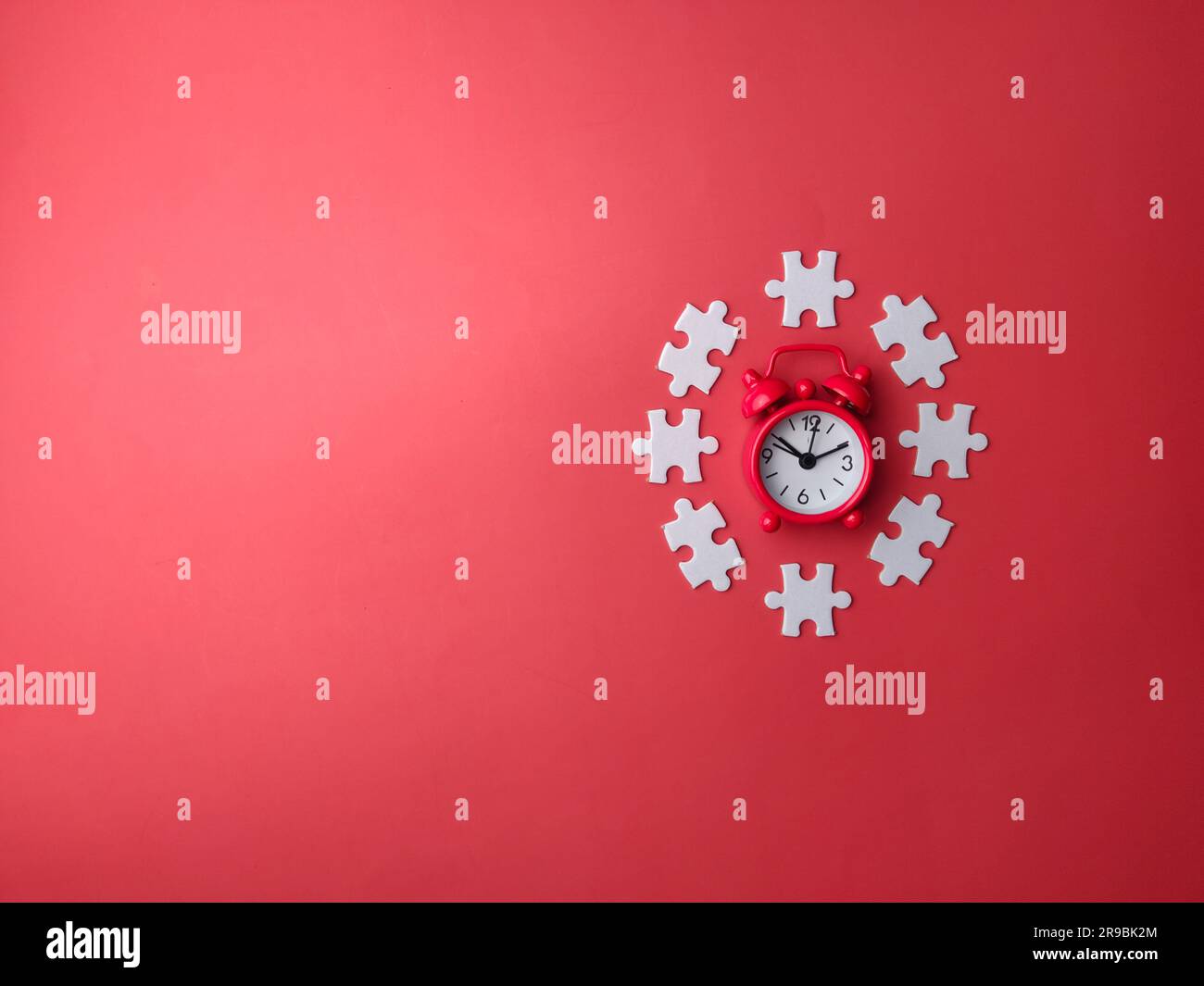 Roter Wecker mit Draufsicht und weißem Puzzle auf rotem Hintergrund mit Kopierbereich Stockfoto
