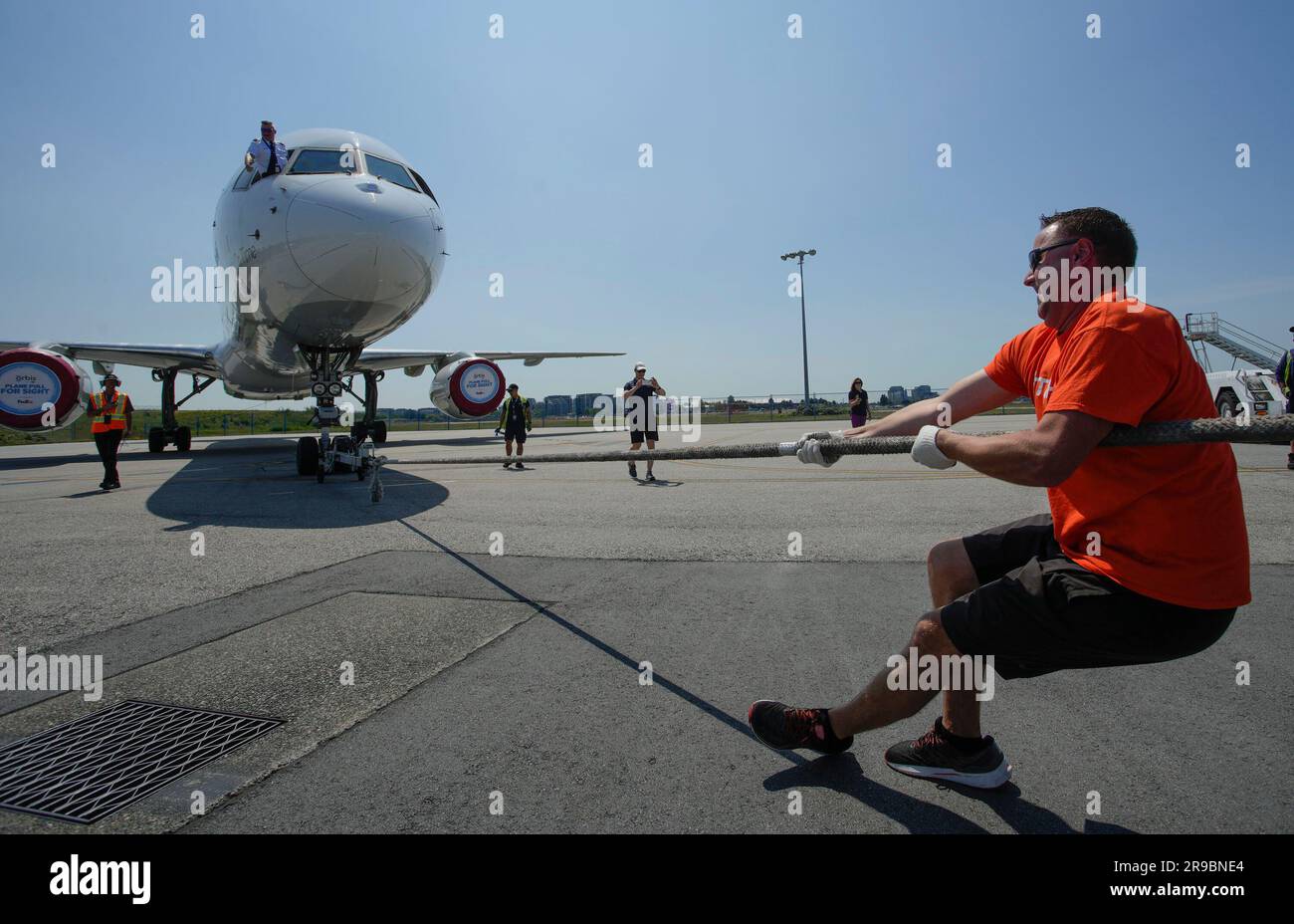 Vancouver, Kanada. 25. Juni 2023. Die Teilnehmer nehmen am 25. Juni 2023 am internationalen Flughafen Vancouver in Vancouver, British Columbia, Kanada, an der Veranstaltung „Flugzeug Pull for Sight“ Teil. Die Teilnehmer nahmen am Sonntag an einer Herausforderung Teil, einen Boeing 757-Jet mit einem Gewicht von mehr als 60.000 Kilogramm über die Rollbahn am Vancouver International Airport zu ziehen, um Geld für Orbis International zu sammeln, damit Orbis International den Gemeinden in Entwicklungsländern grundlegende Augenpflegedienste anbieten kann. Kredit: Liang Sen/Xinhua/Alamy Live News Stockfoto