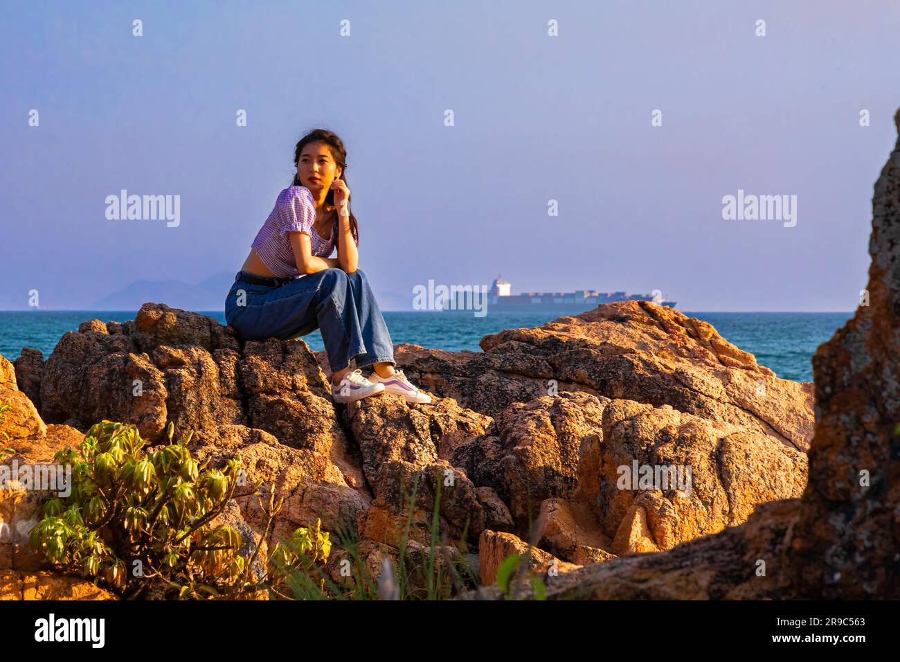 Chinesisches Mädchen, das für ein Foto auf Felsen posiert, Stanley Harbour, Hongkong, SAR, China Stockfoto