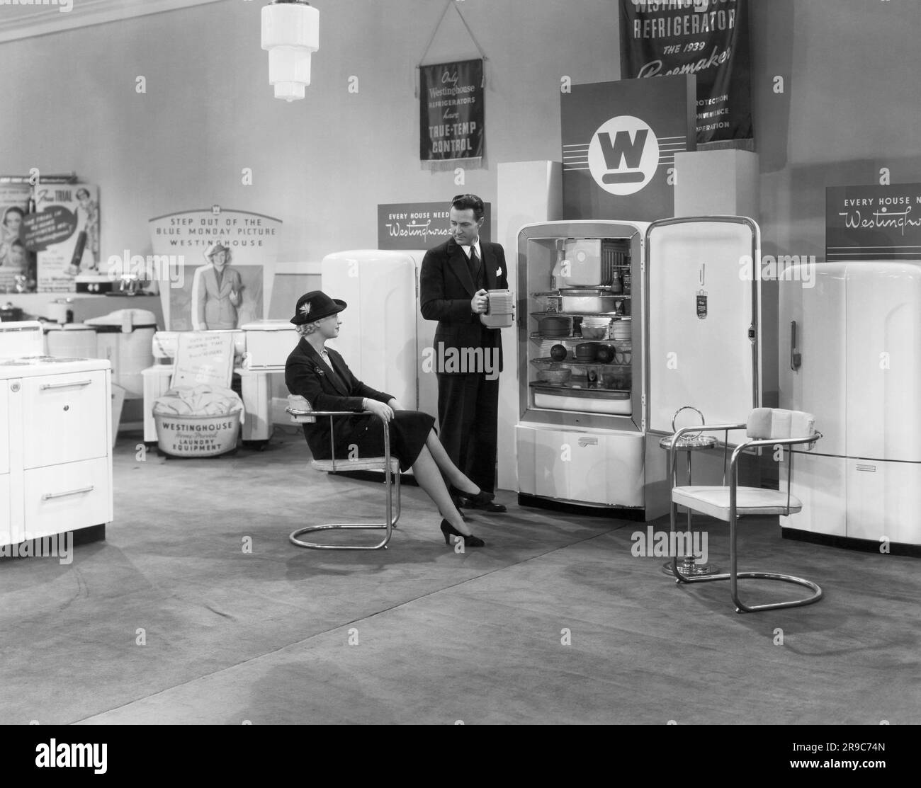 USA: 1939 Ein Verkäufer präsentiert einer Frau in einem Ausstellungsraum für Geräte von Westinghouse die Vorzüge von Kühlschränken von Westinghouse. Stockfoto