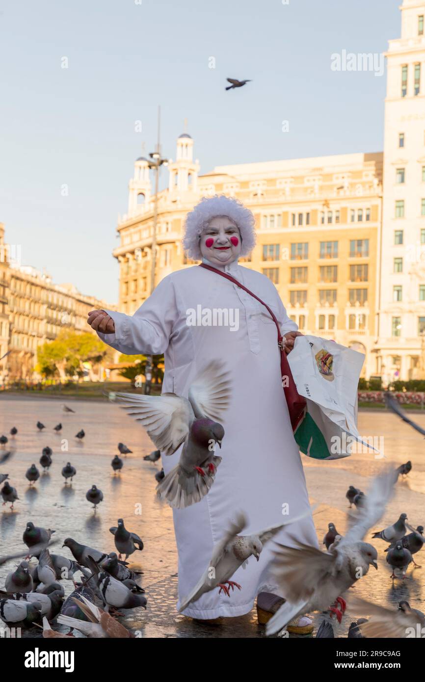 Barcelona, Spanien - 10. Februar 2022: Seniorin in weißer Maske und Kostüm, die Reis verkauft, um die Tauben am Catalonia Square in Barcelona, S. zu füttern Stockfoto