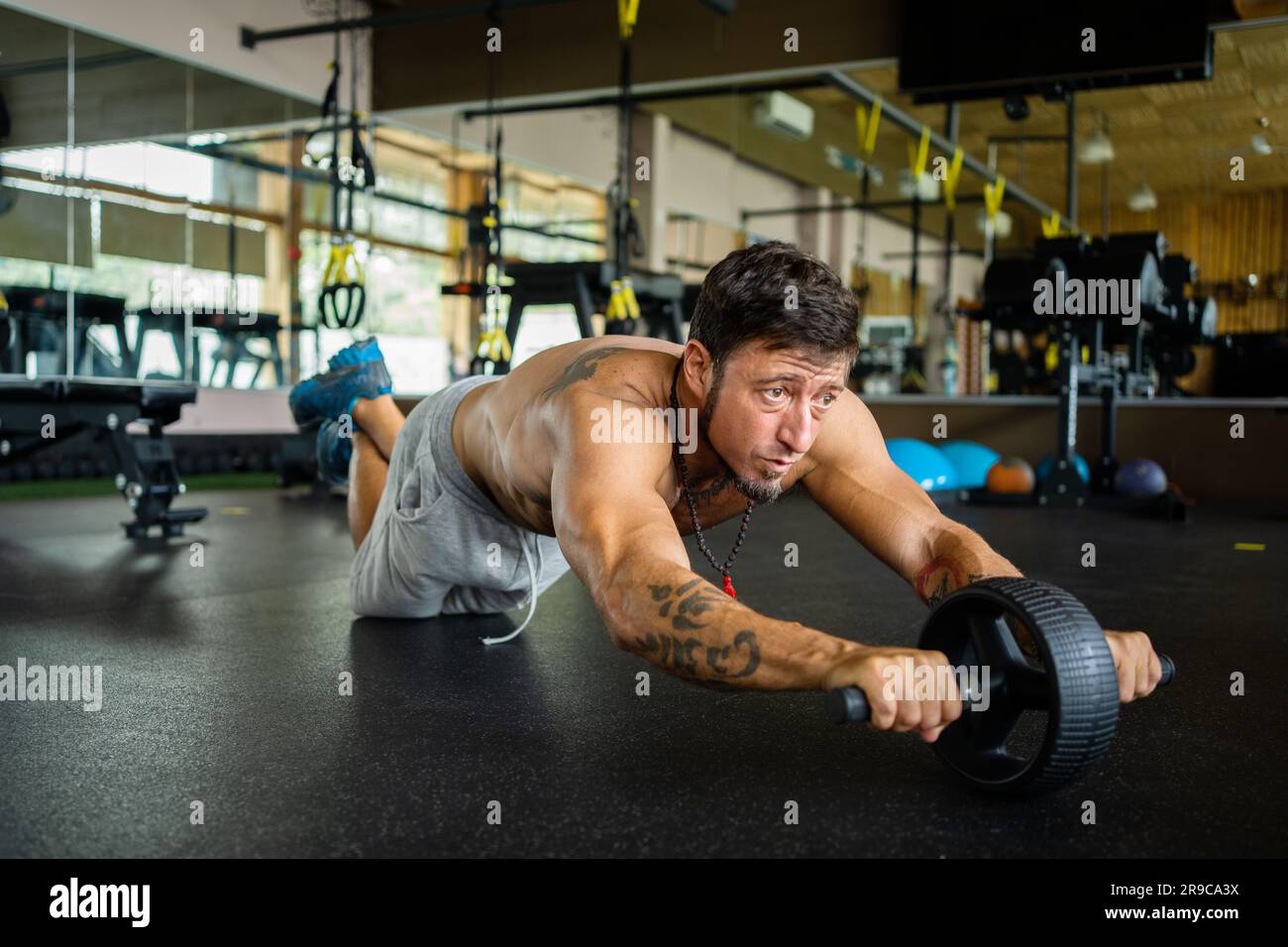 Porträt eines starken Mannes, der das Bauchrad im Fitnessstudio benutzt Stockfoto