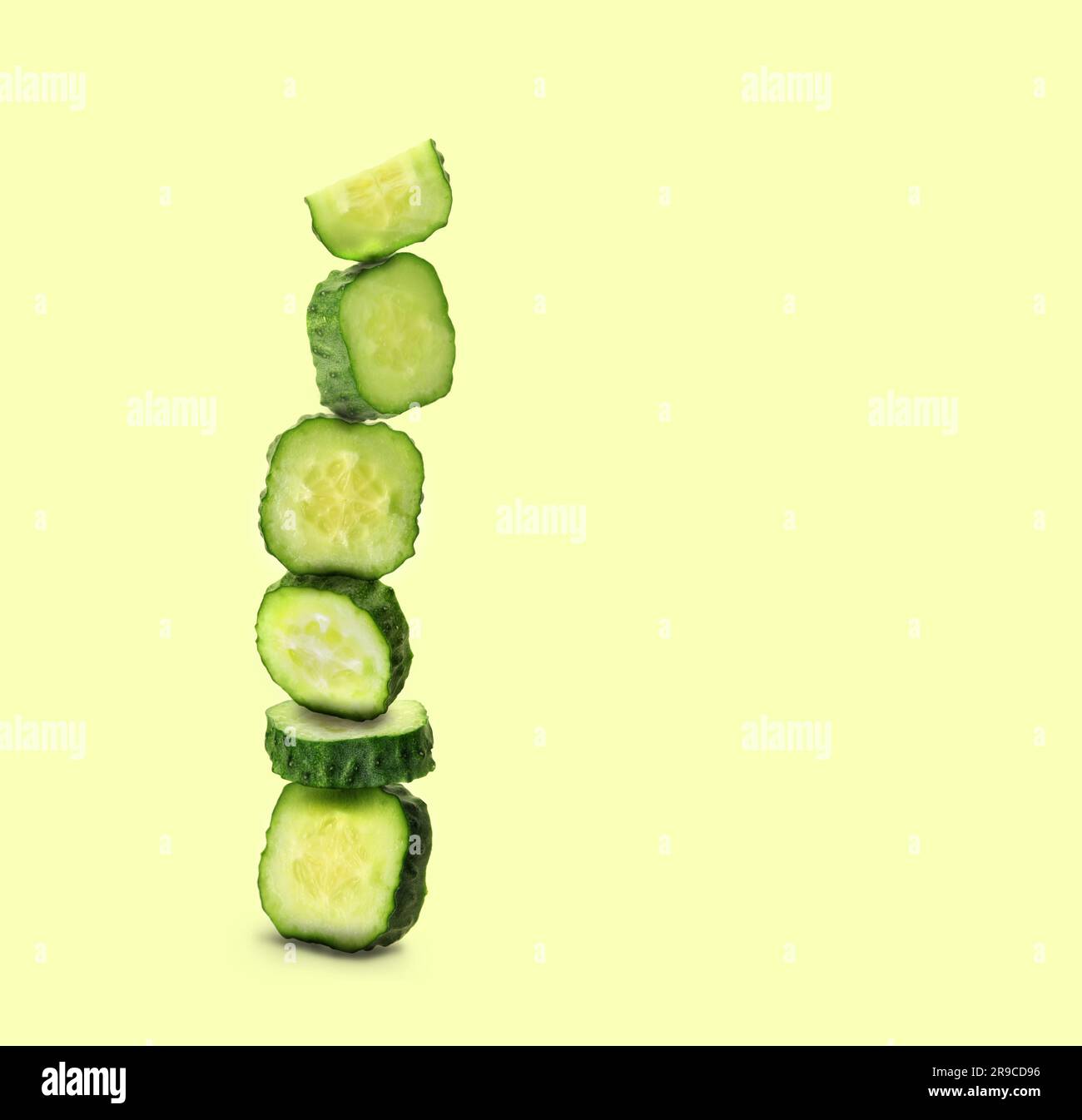 Stapel frischer Gurkenstücke auf hellgelbem grünen Hintergrund, Platz für Text Stockfoto