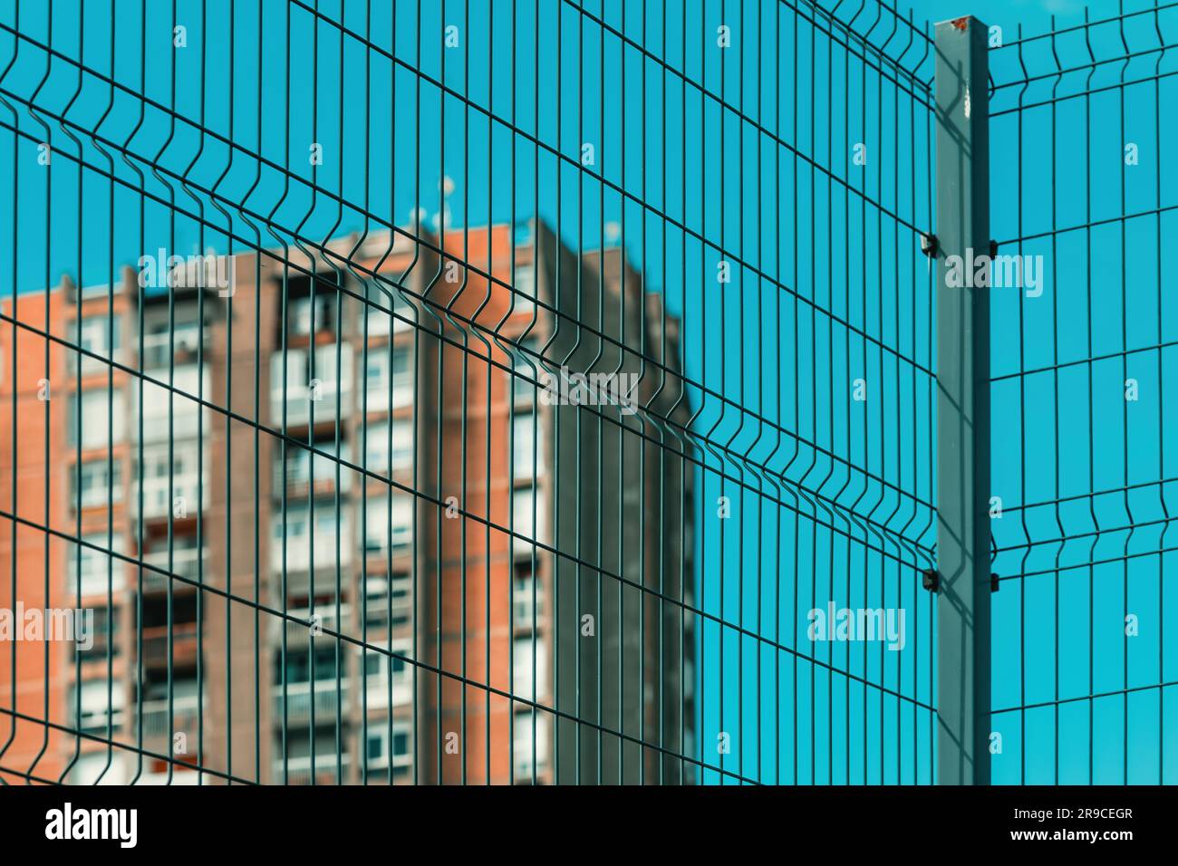 Hohes Gebäude im brutalistischen Stil hinter einem Metallzaun, selektiver Fokus Stockfoto