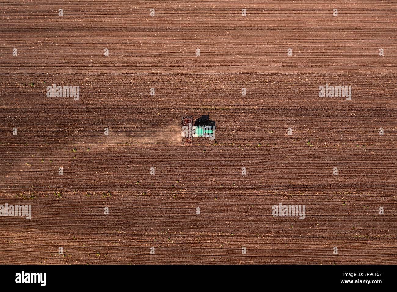 Landwirtschaftstraktor mit angekoppelter Deichsel, der die Feldarbeit vor der Aussaat durchführt, Luftaufnahme von der Drohne aus gesehen von oben nach unten Stockfoto