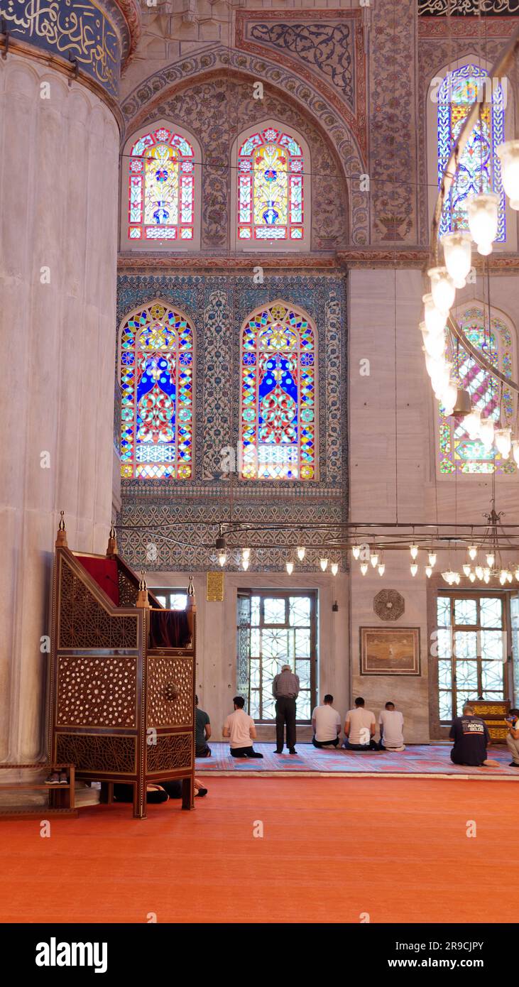 Männer beten in der Sultan-Ahmed-Moschee, auch bekannt als Blaue Moschee Istanbul, Türkei. Hölzerne Minibar alias Kanzel links Stockfoto