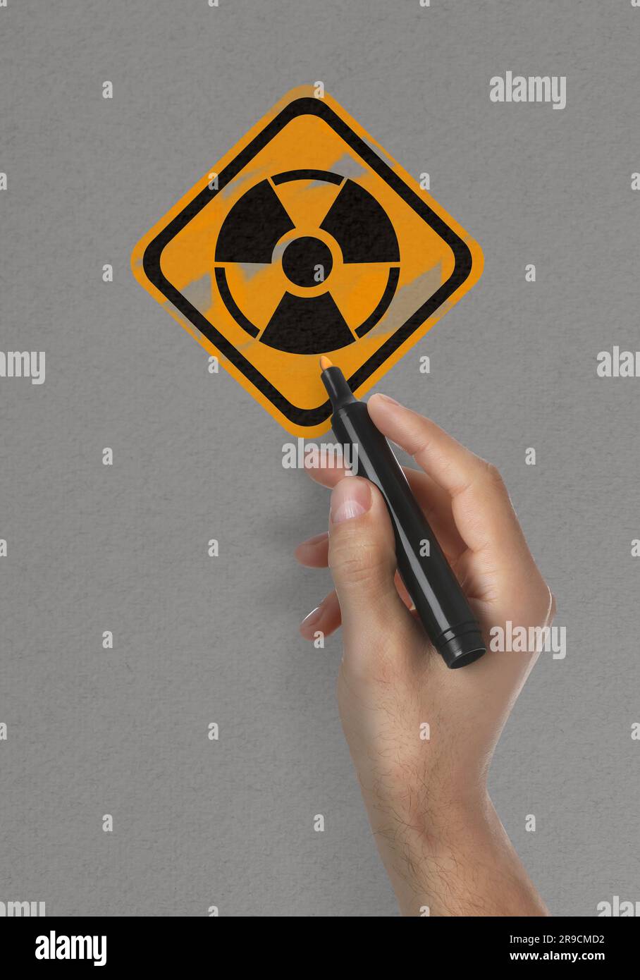 Man malt Strahlungswarnsymbol mit Markierung auf hellgrauer Oberfläche, Nahaufnahme Stockfoto