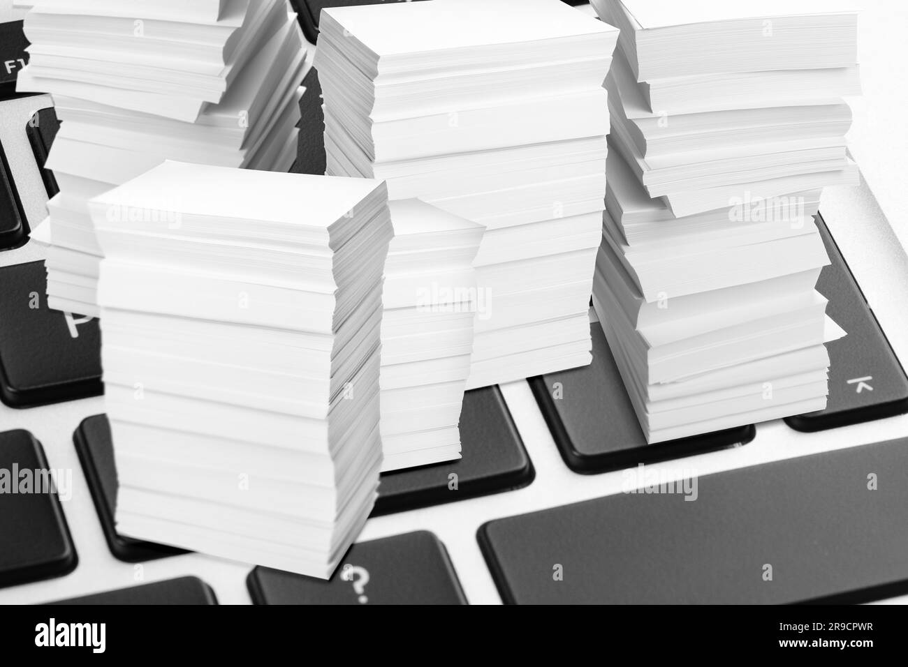 Digitales Archiv. Laptop-Tastatur mit verkleinertem gestapeltem Papier, Nahaufnahme Stockfoto