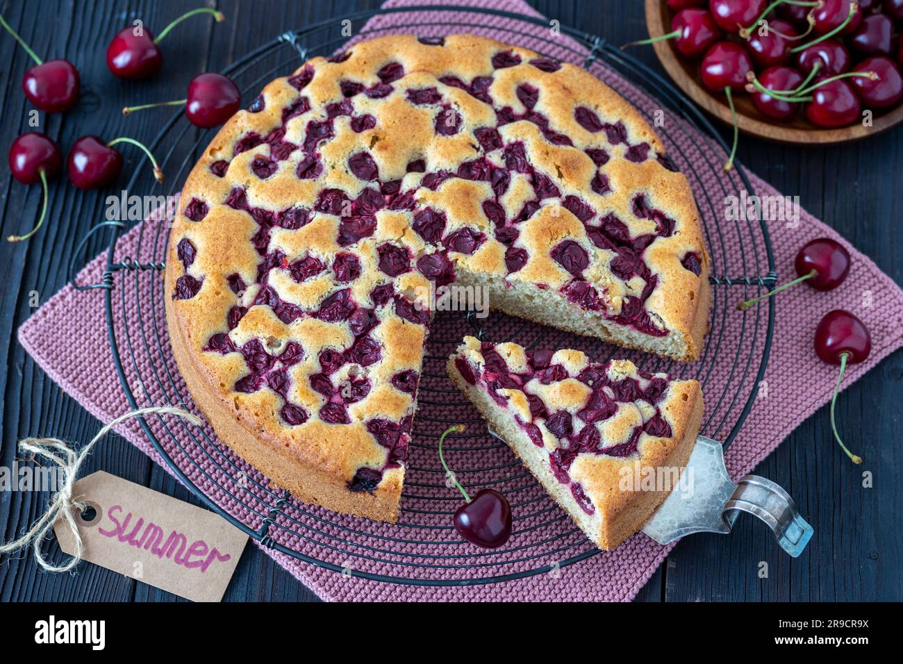 Kirschkuchen auf dem Kuchengitter und frische süße Kirschen Stockfoto