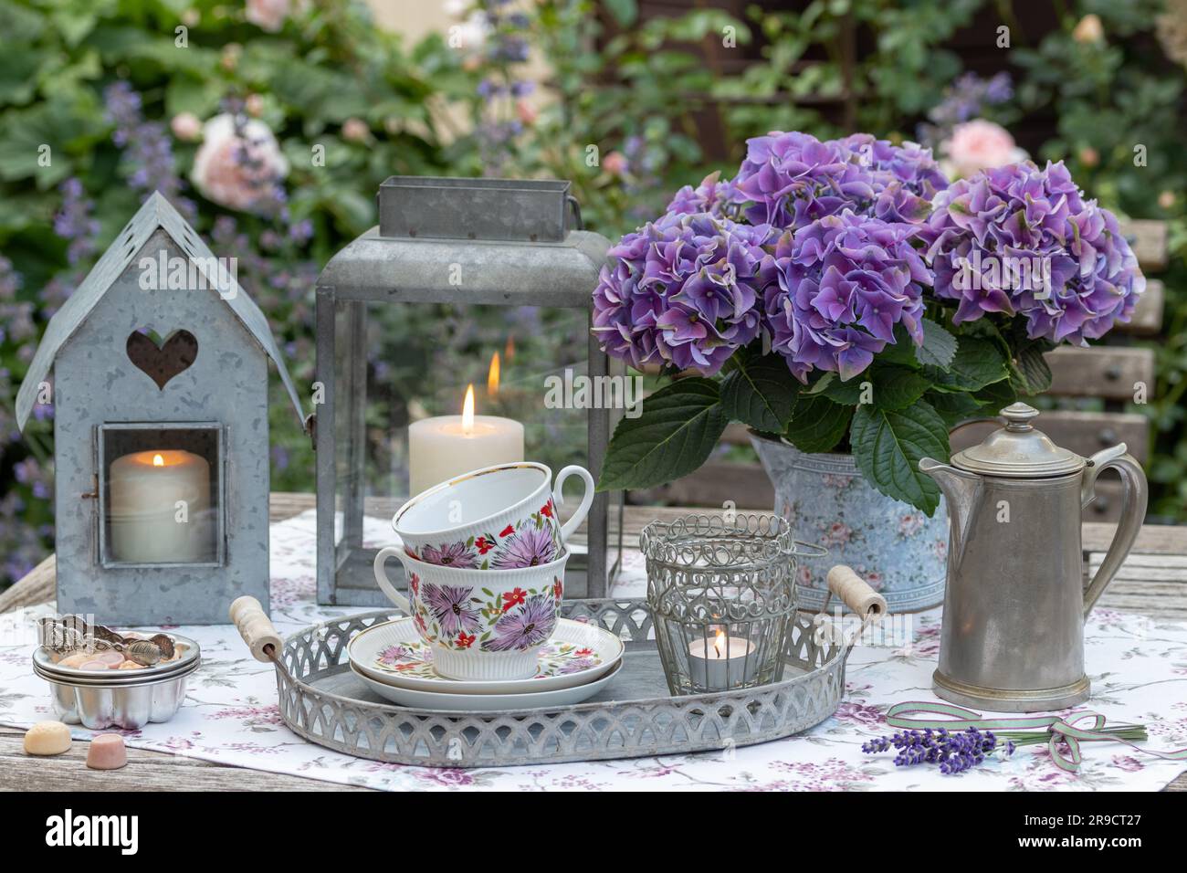 Tischaufteilung mit Porzellanbechern, lila Hortensien und Vintage-Laternen Stockfoto